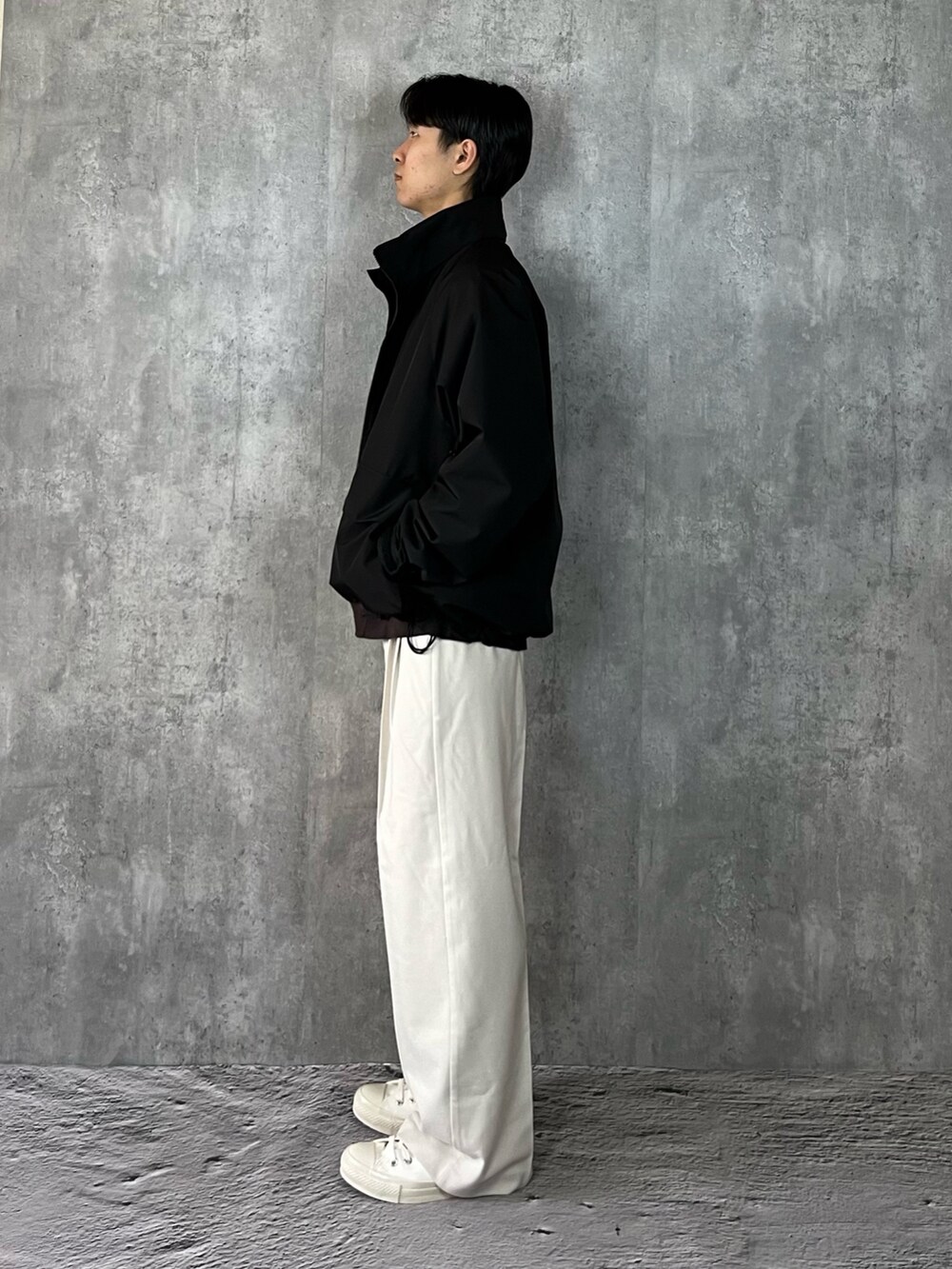 ホワイト系のスニーカー、ホワイト系のスラックス、ブラック系のブルゾンを着用したメンズの冬コーディネートの3枚目の写真