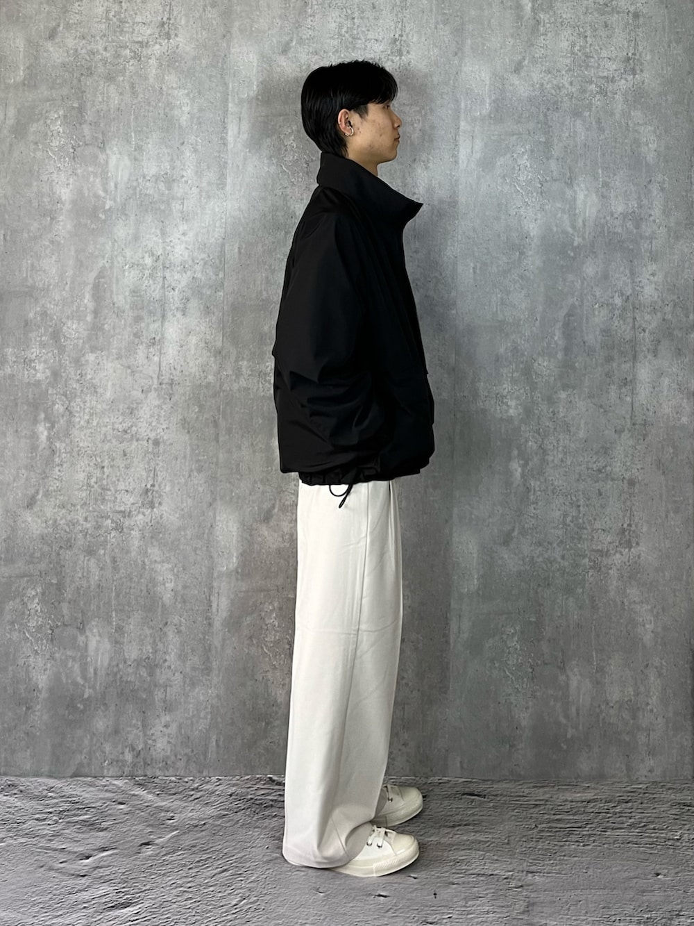 ホワイト系のスニーカー、ホワイト系のスラックス、ブラック系のブルゾンを着用したメンズの冬コーディネートの4枚目の写真