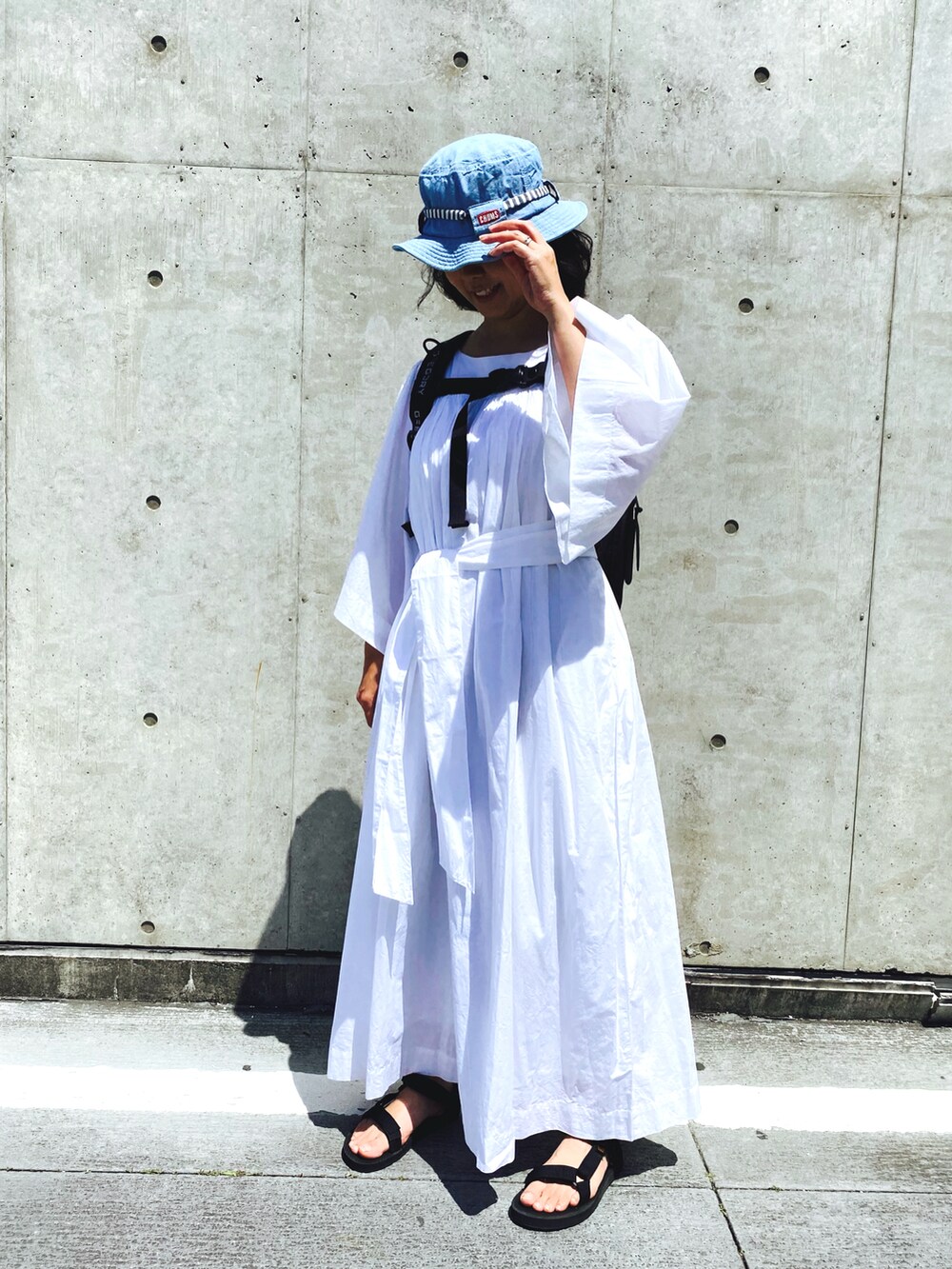 ホワイト系のワンピース、ブラック系のサンダル、ブラック系のバックパック/リュックを着用したレディースの春コーディネートの2枚目の写真