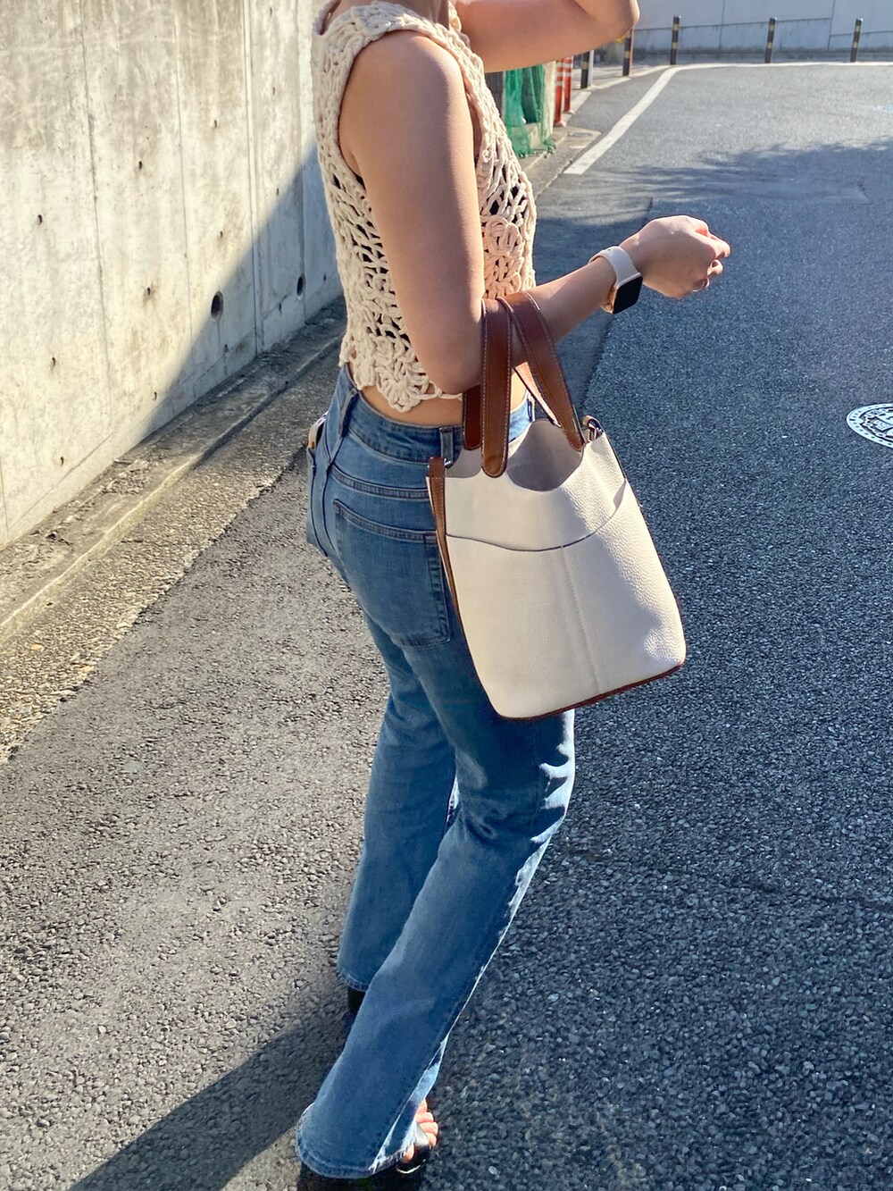 ベージュ系のタンクトップ、ブルー系のデニムパンツ、ホワイト系のハンドバッグを着用したレディースの夏コーディネートの2枚目の写真