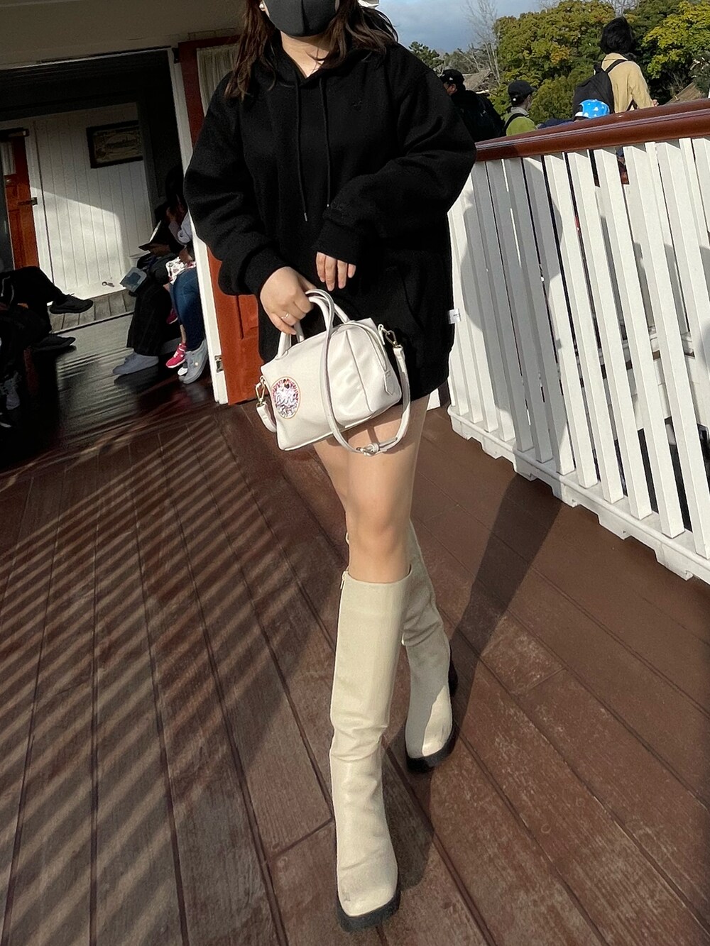 ブラック系のパーカー、ホワイト系のブーツを着用したレディースの春コーディネートの2枚目の写真