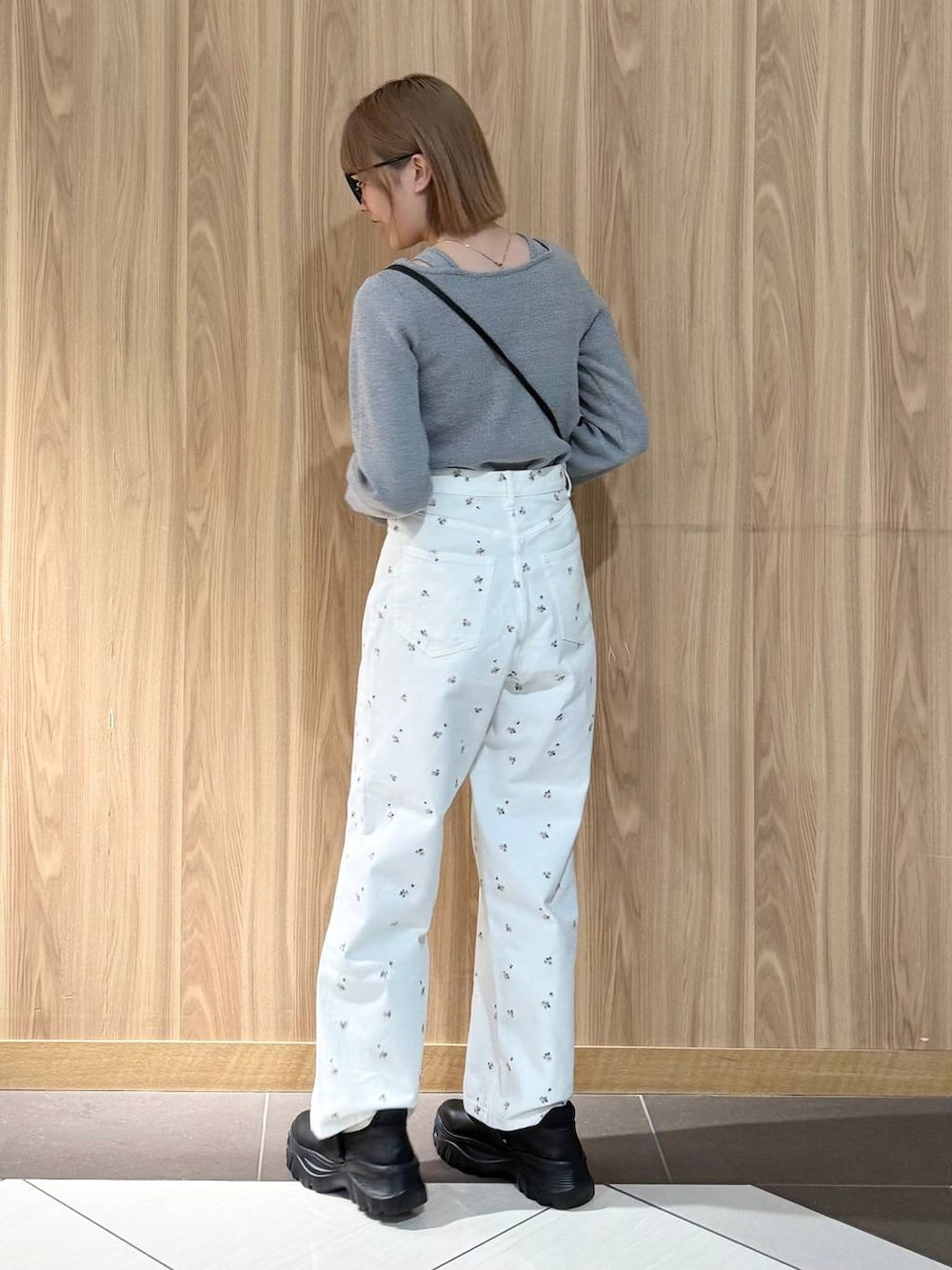 ブラック系のスニーカー、ブラック系のハンドバッグ、ホワイト系のデニムパンツを着用したレディースの春コーディネートの3枚目の写真