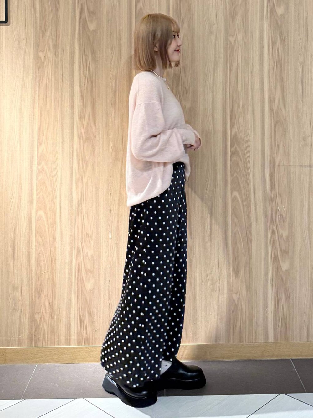 ブラック系のスカート、ブラック系のサンダル、ピンク系のニット/セーターを着用したレディースの秋コーディネートの2枚目の写真