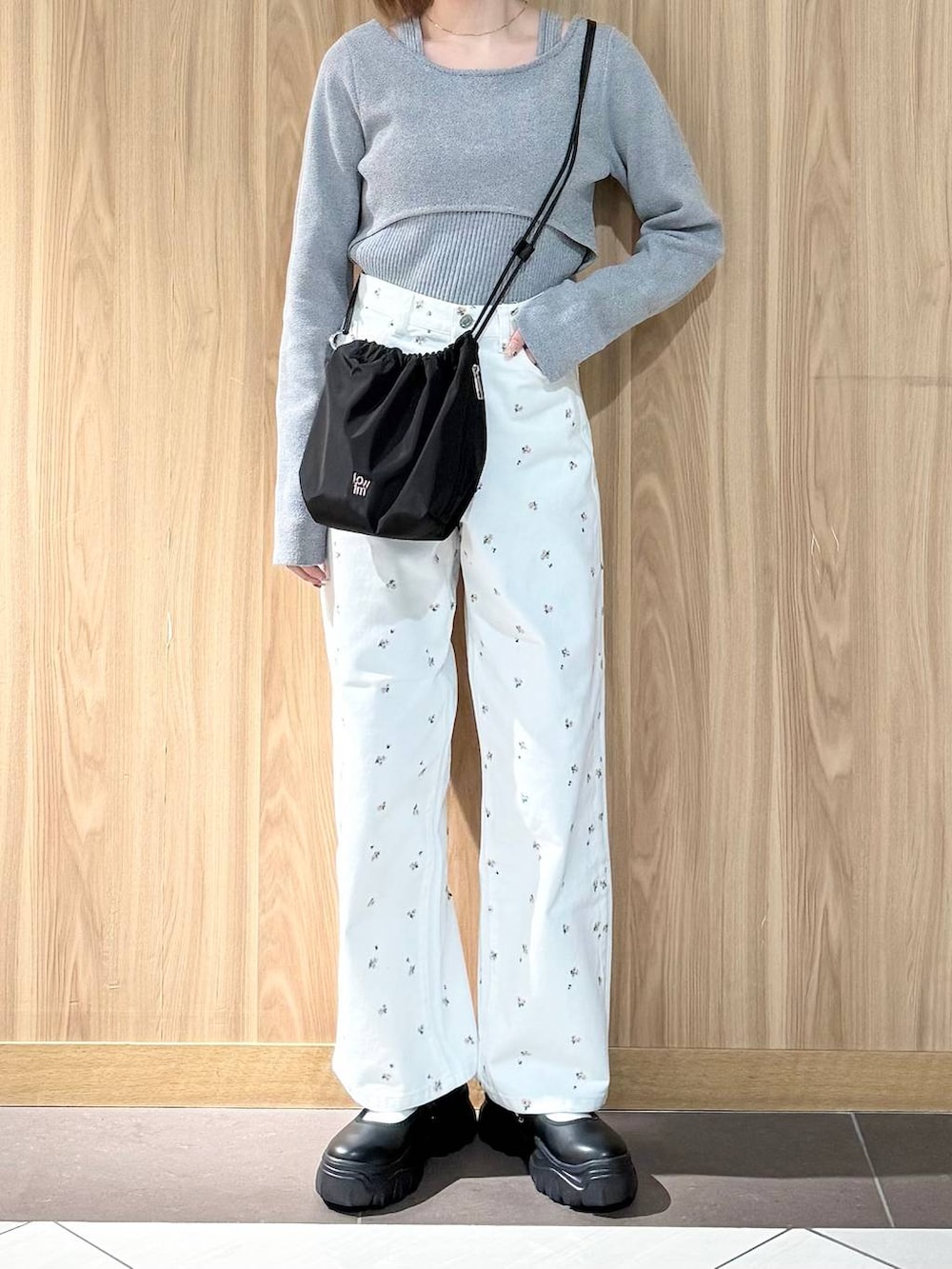 ブラック系のスニーカー、ブラック系のハンドバッグ、ホワイト系のデニムパンツを着用したレディースの春コーディネートの5枚目の写真