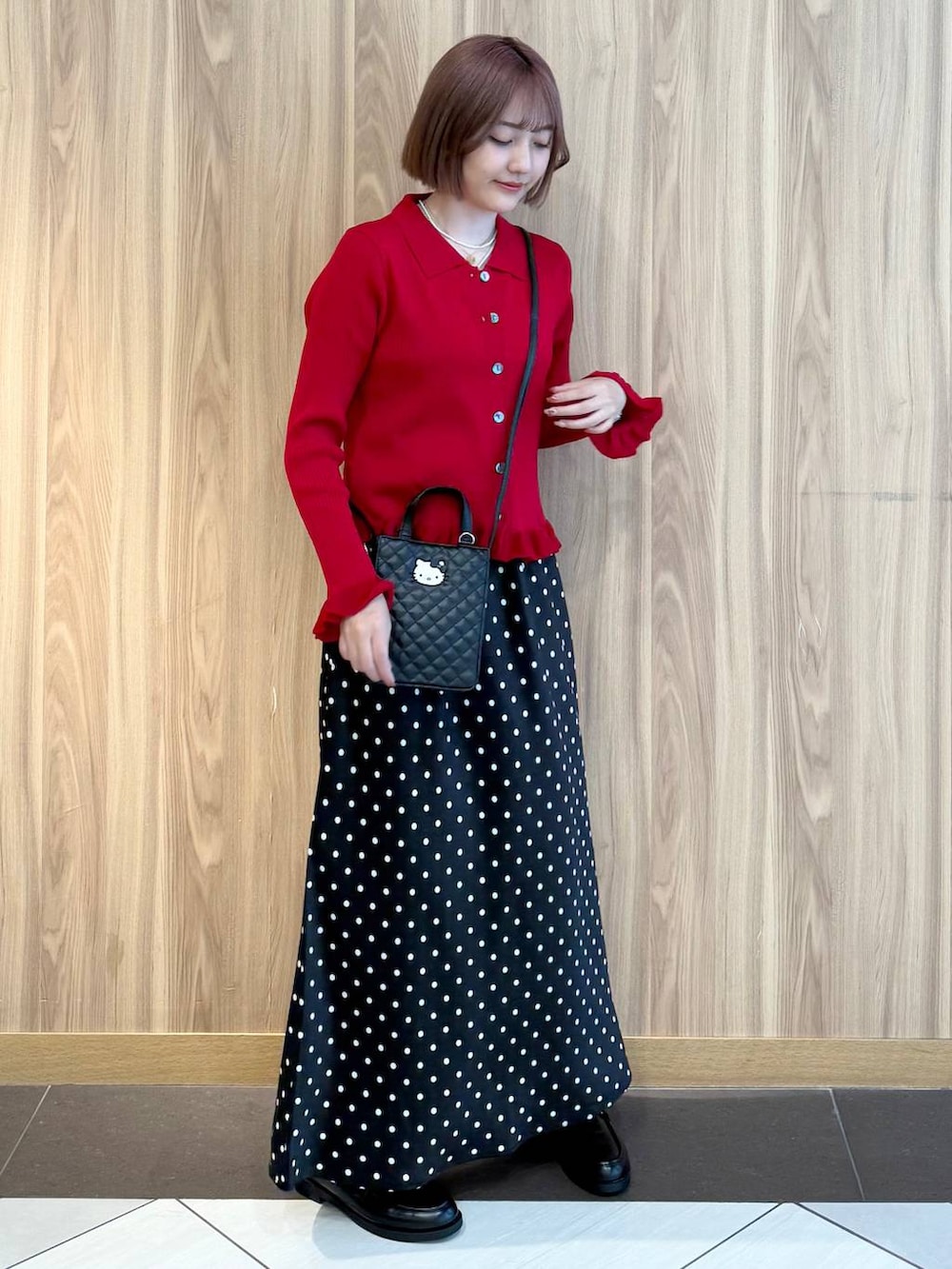 ブラック系のスカート、レッド系のニット/セーター、ブラック系のローファーを着用したレディースの秋コーディネートの2枚目の写真