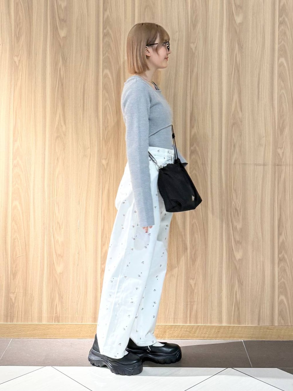 ブラック系のスニーカー、ブラック系のハンドバッグ、ホワイト系のデニムパンツを着用したレディースの春コーディネートの2枚目の写真