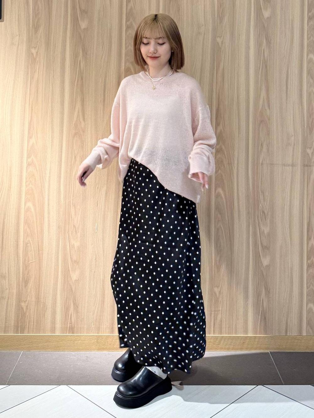 ブラック系のスカート、ブラック系のサンダル、ピンク系のニット/セーターを着用したレディースの秋コーディネートの4枚目の写真