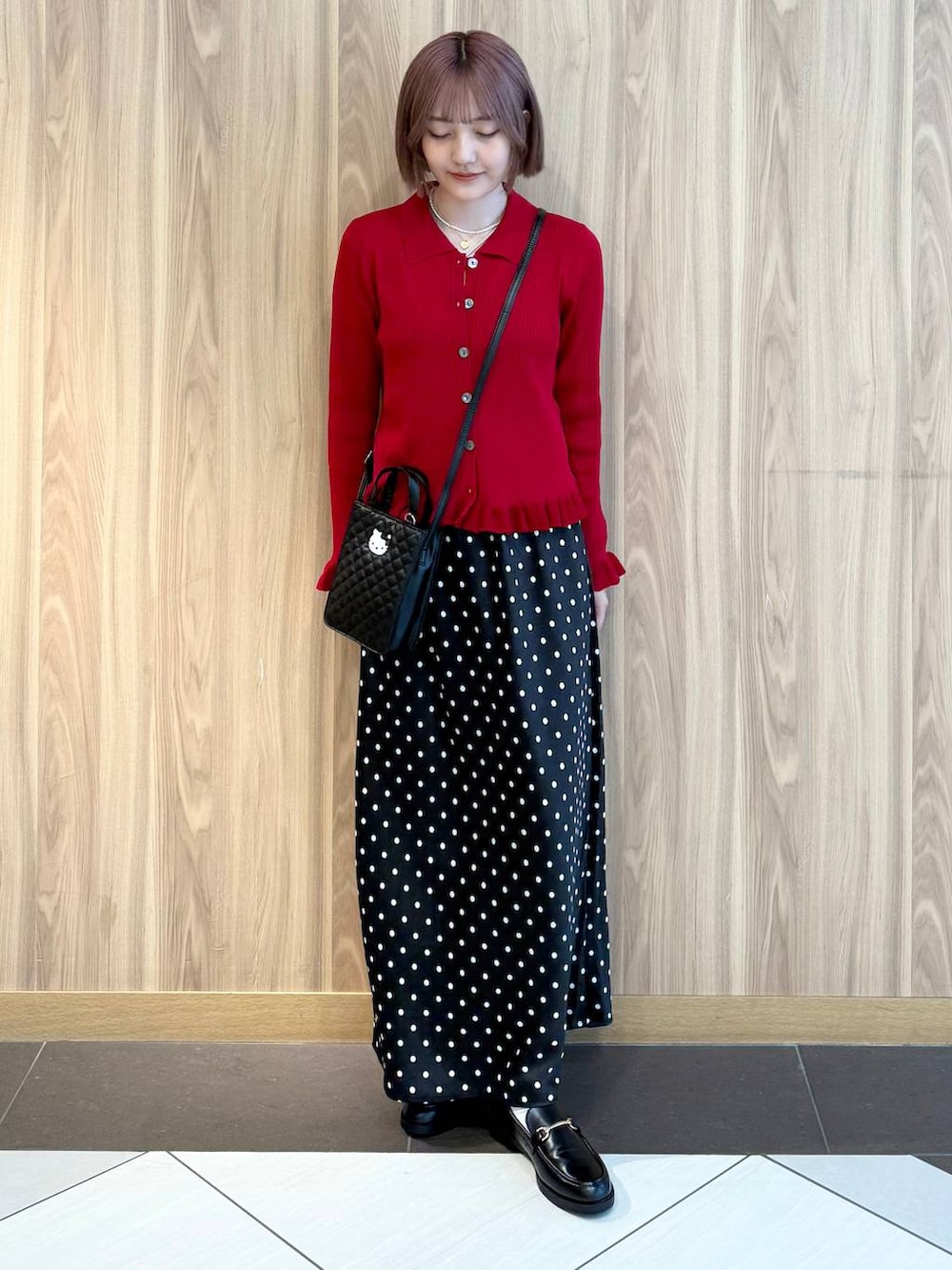 ブラック系のスカート、レッド系のニット/セーター、ブラック系のローファーを着用したレディースの秋コーディネートの4枚目の写真