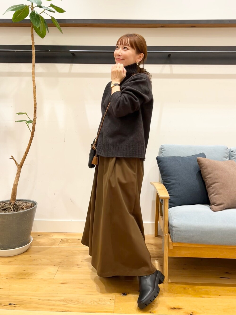 ブルー系のニット/セーター、ブラック系のショルダーバッグ、ブラウン系のスカートを着用したレディースの冬コーディネートの2枚目の写真