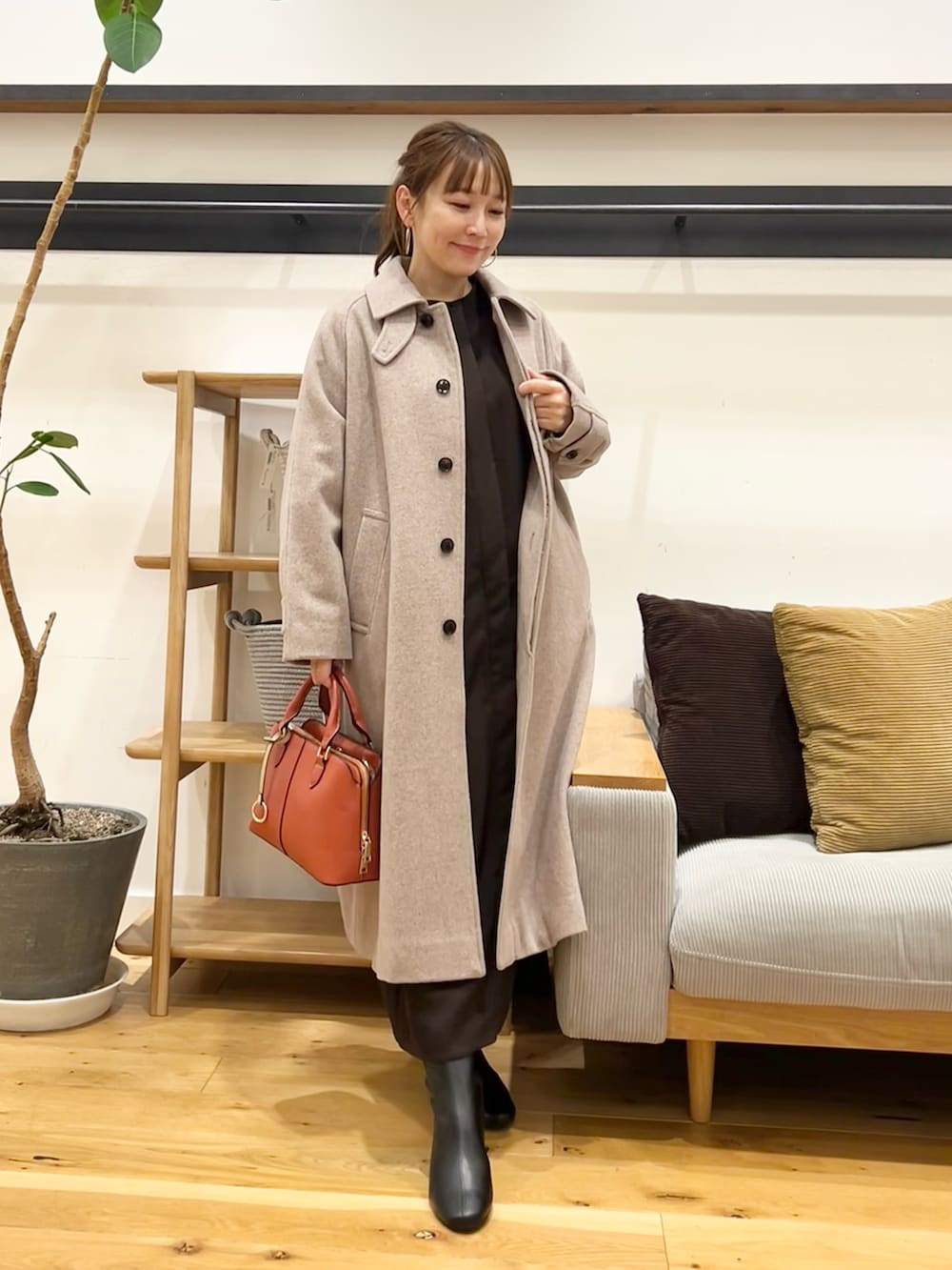 ブラウン系のワンピース、ブラック系のハンドバッグ、ブラック系のブーツを着用したレディースの冬コーディネートの5枚目の写真