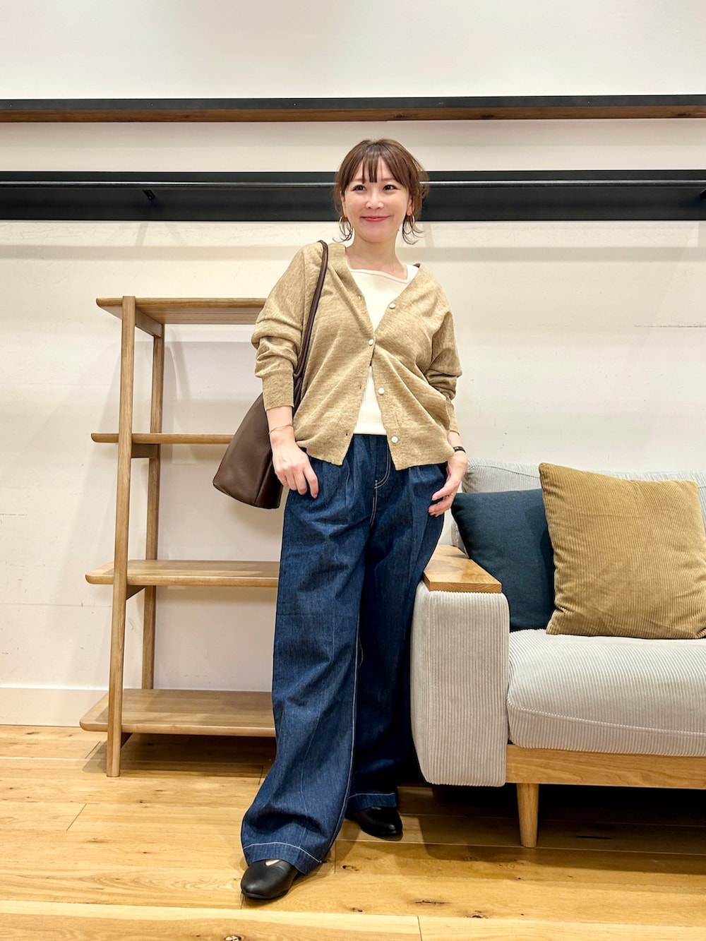 ベージュ系のカーディガン/ボレロ、ホワイト系のタンクトップ、ブルー系のデニムパンツを着用したレディースの春コーディネートの5枚目の写真