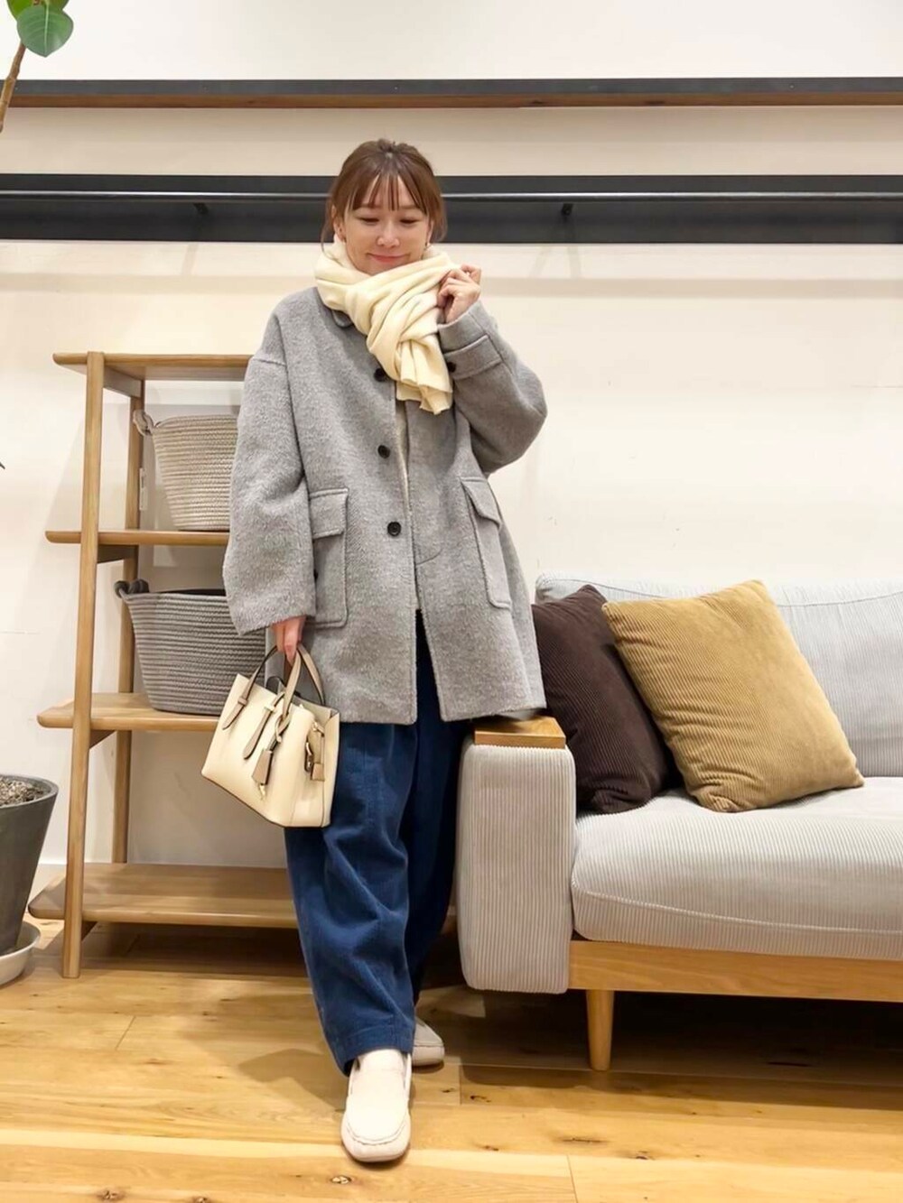 ホワイト系のハンドバッグ、グレー系のその他アウター、ホワイト系のスリッポンを着用したレディースの冬コーディネートの7枚目の写真