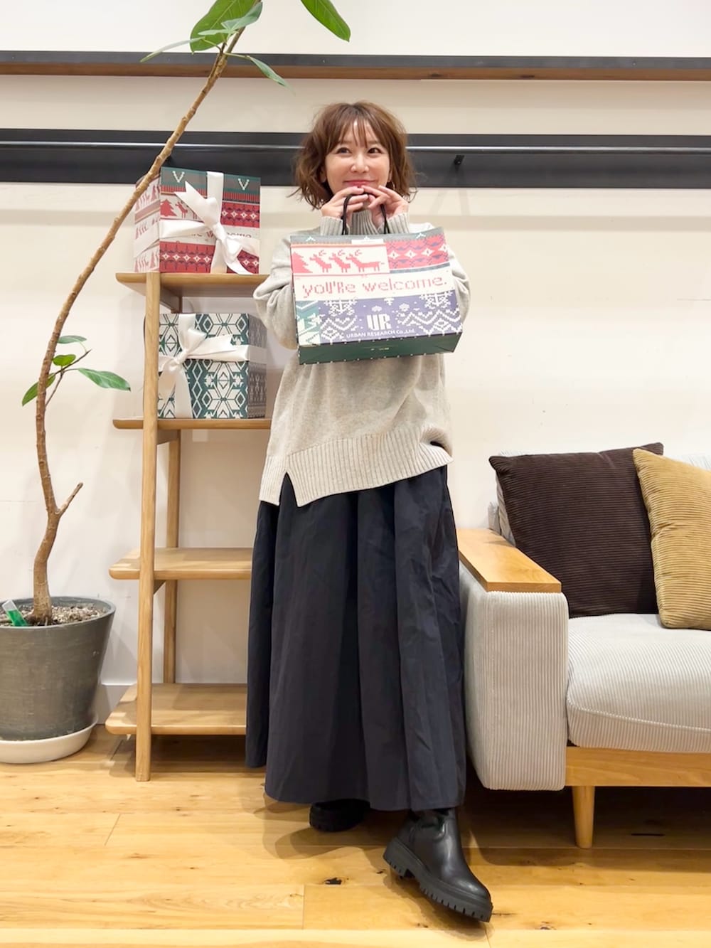 グレー系のニット/セーター、ブルー系のスカート、ブラック系のブーツを着用したレディースの冬コーディネートの6枚目の写真