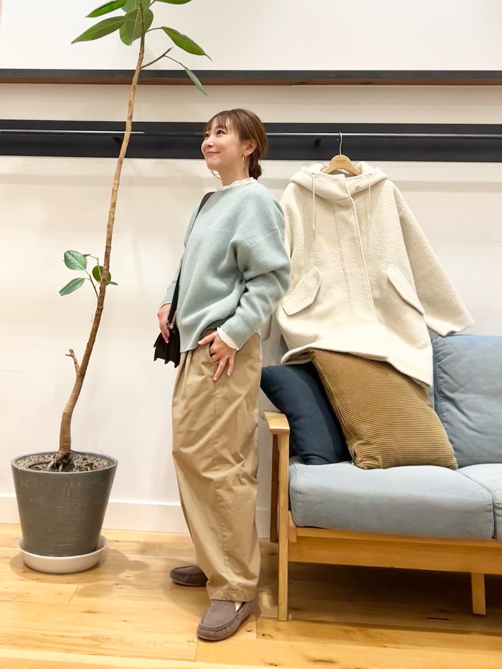 グリーン系のニット/セーター、ベージュ系のその他パンツ、ホワイト系のシャツ/ブラウスを着用したレディースの冬コーディネートの2枚目の写真