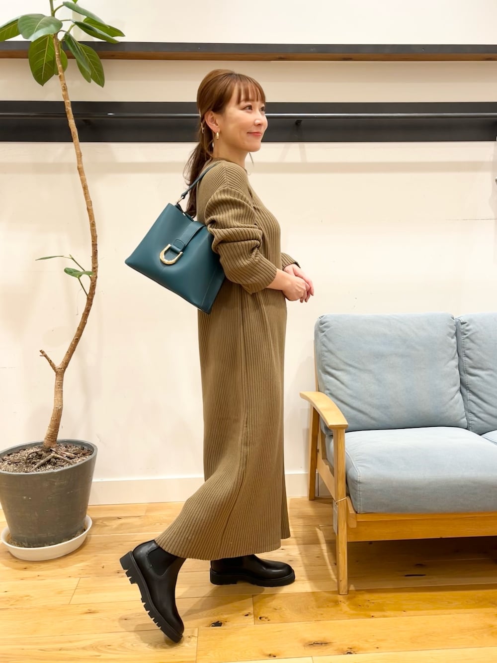 ブラウン系のワンピース、ブルー系のハンドバッグ、ブラック系のブーツを着用したレディースの冬コーディネートの4枚目の写真