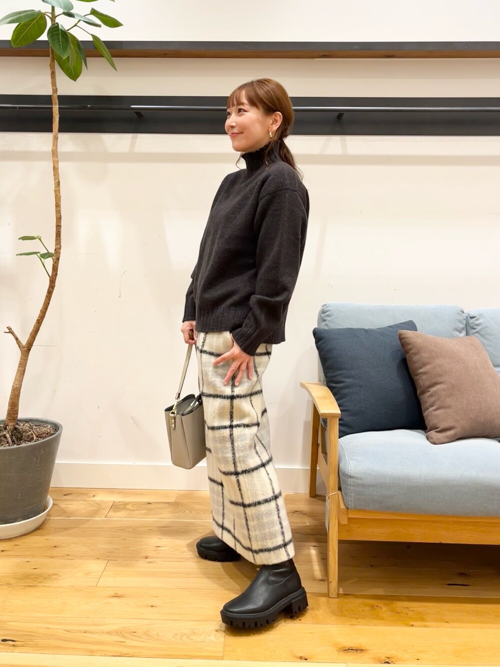 ブルー系のニット/セーター、ベージュ系のスカート、グレー系のショルダーバッグを着用したレディースの冬コーディネートの2枚目の写真