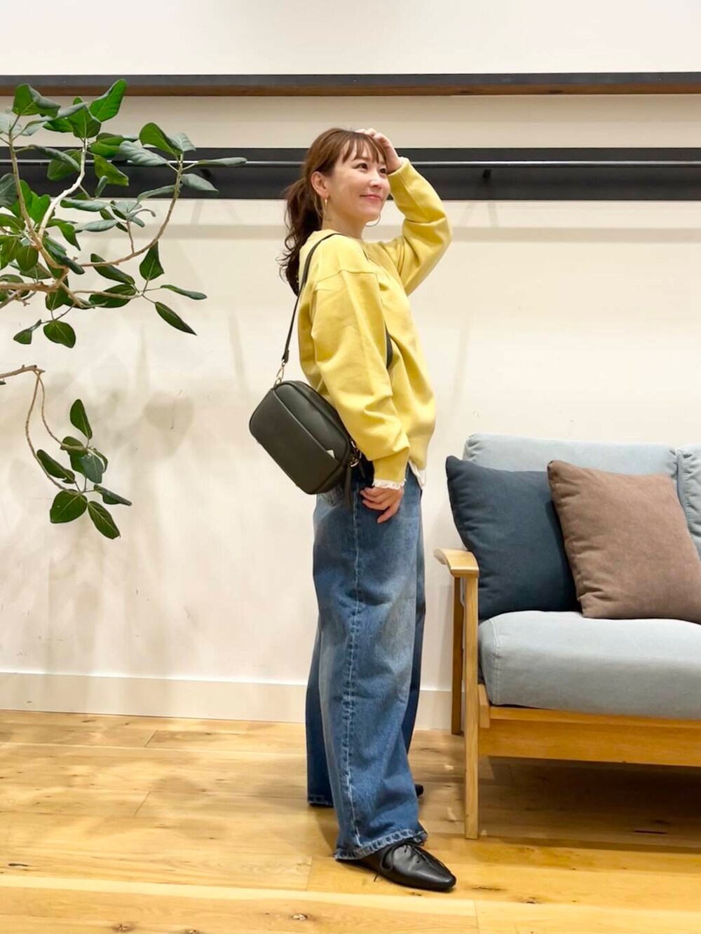 ブルー系のデニムパンツ、グリーン系のショルダーバッグ、ブラック系のその他シューズを着用したレディースの秋コーディネートの2枚目の写真