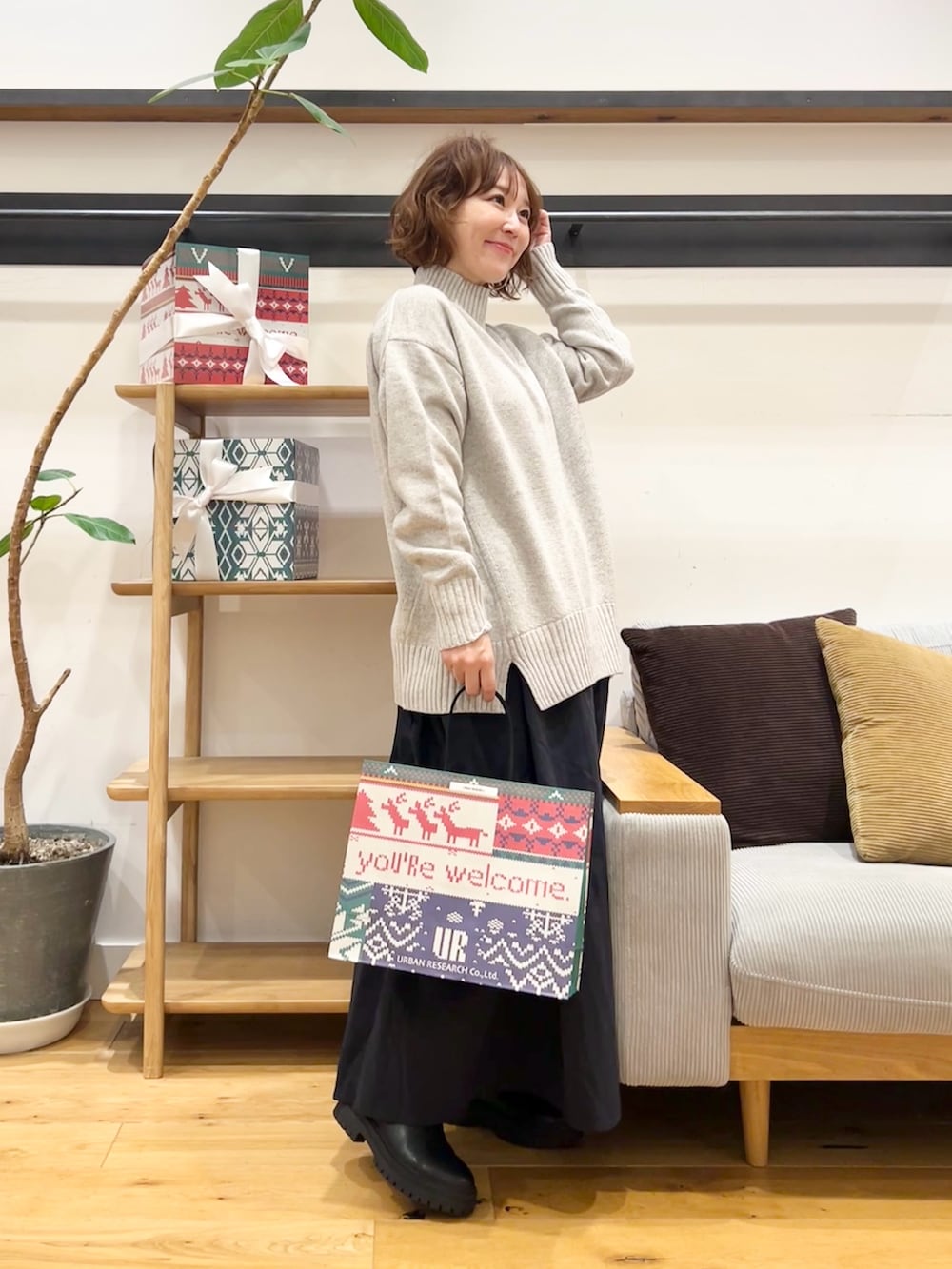 グレー系のニット/セーター、ブルー系のスカート、ブラック系のブーツを着用したレディースの冬コーディネートの2枚目の写真