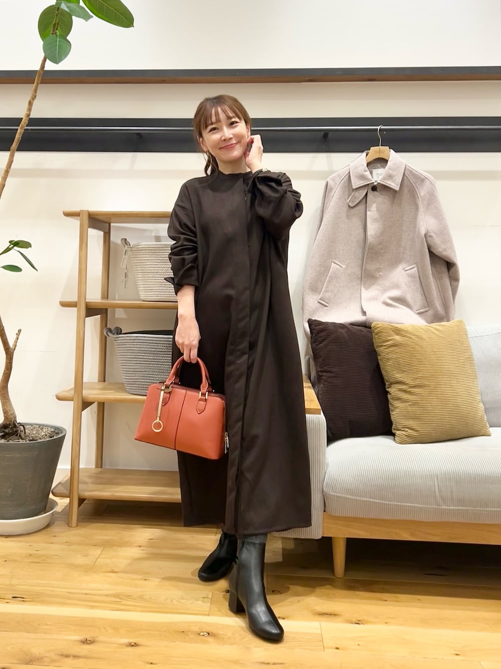 ブラウン系のワンピース、ブラック系のハンドバッグ、ブラック系のブーツを着用したレディースの冬コーディネートの4枚目の写真