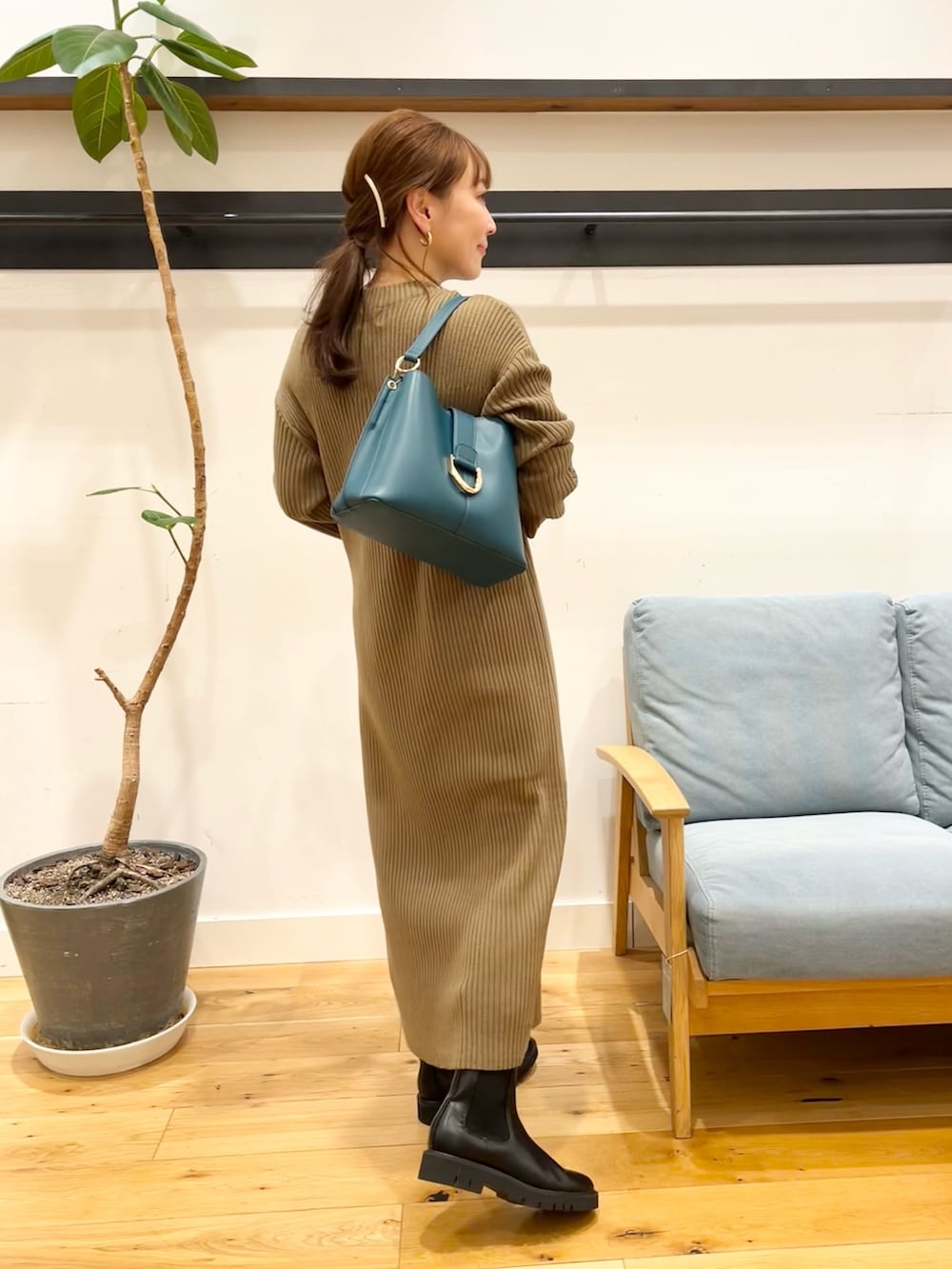 ブラウン系のワンピース、ブルー系のハンドバッグ、ブラック系のブーツを着用したレディースの冬コーディネートの2枚目の写真