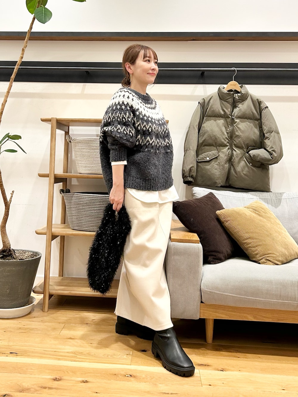 グレー系のニット/セーター、ブラウン系のトートバッグ、ホワイト系のスカートを着用したレディースの冬コーディネートの4枚目の写真