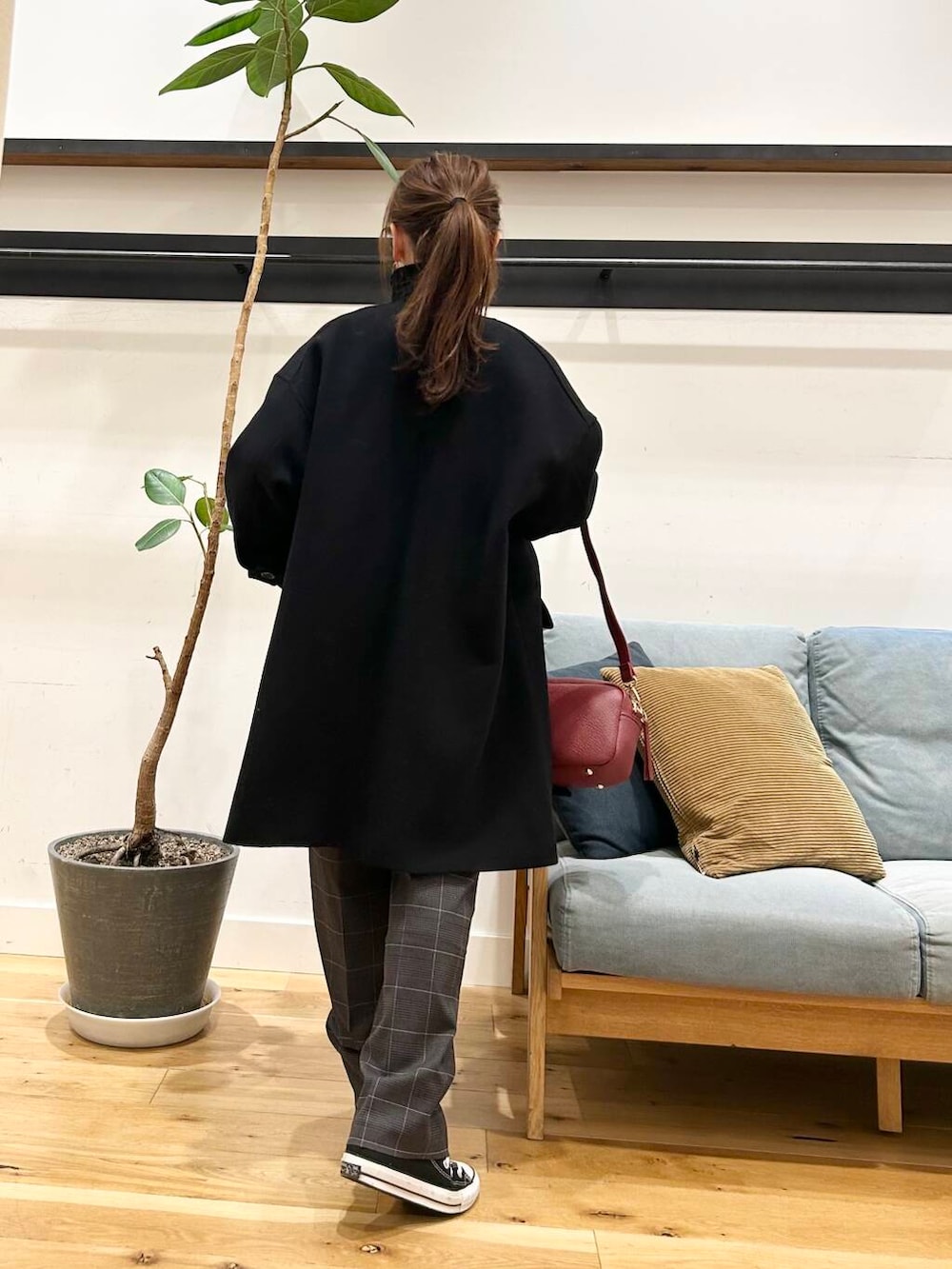 ブラック系のノーカラーコート、レッド系のショルダーバッグ、ブラック系のニット/セーターを着用したレディースの冬コーディネートの6枚目の写真