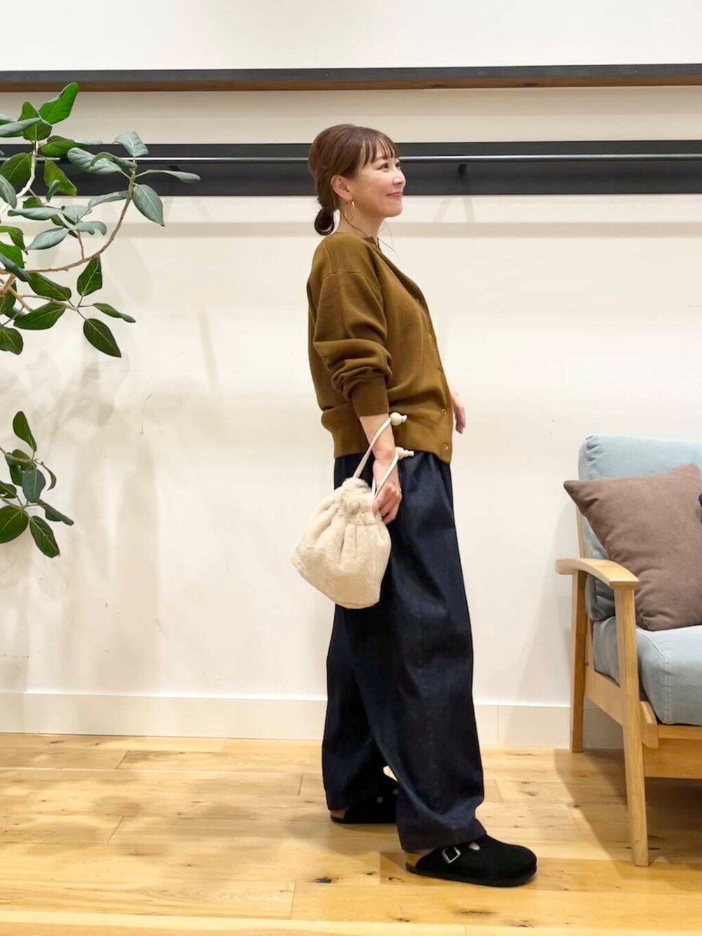 ブルー系のデニムパンツ、イエロー系のカーディガン/ボレロ、ホワイト系のショルダーバッグを着用したレディースの秋コーディネートの4枚目の写真