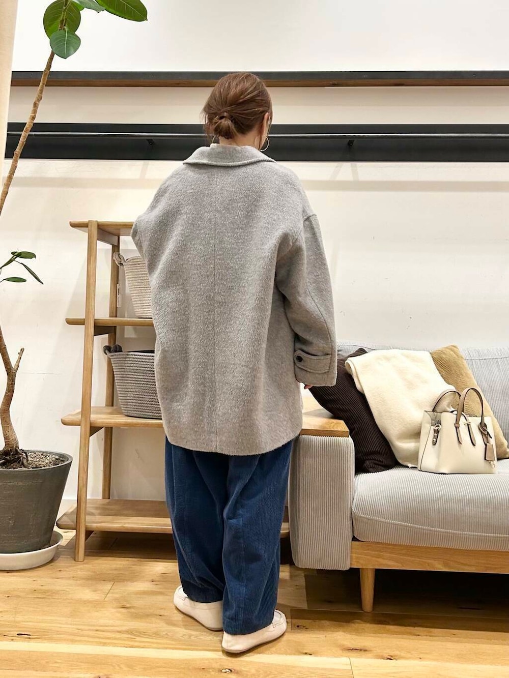 ホワイト系のハンドバッグ、グレー系のその他アウター、ホワイト系のスリッポンを着用したレディースの冬コーディネートの5枚目の写真