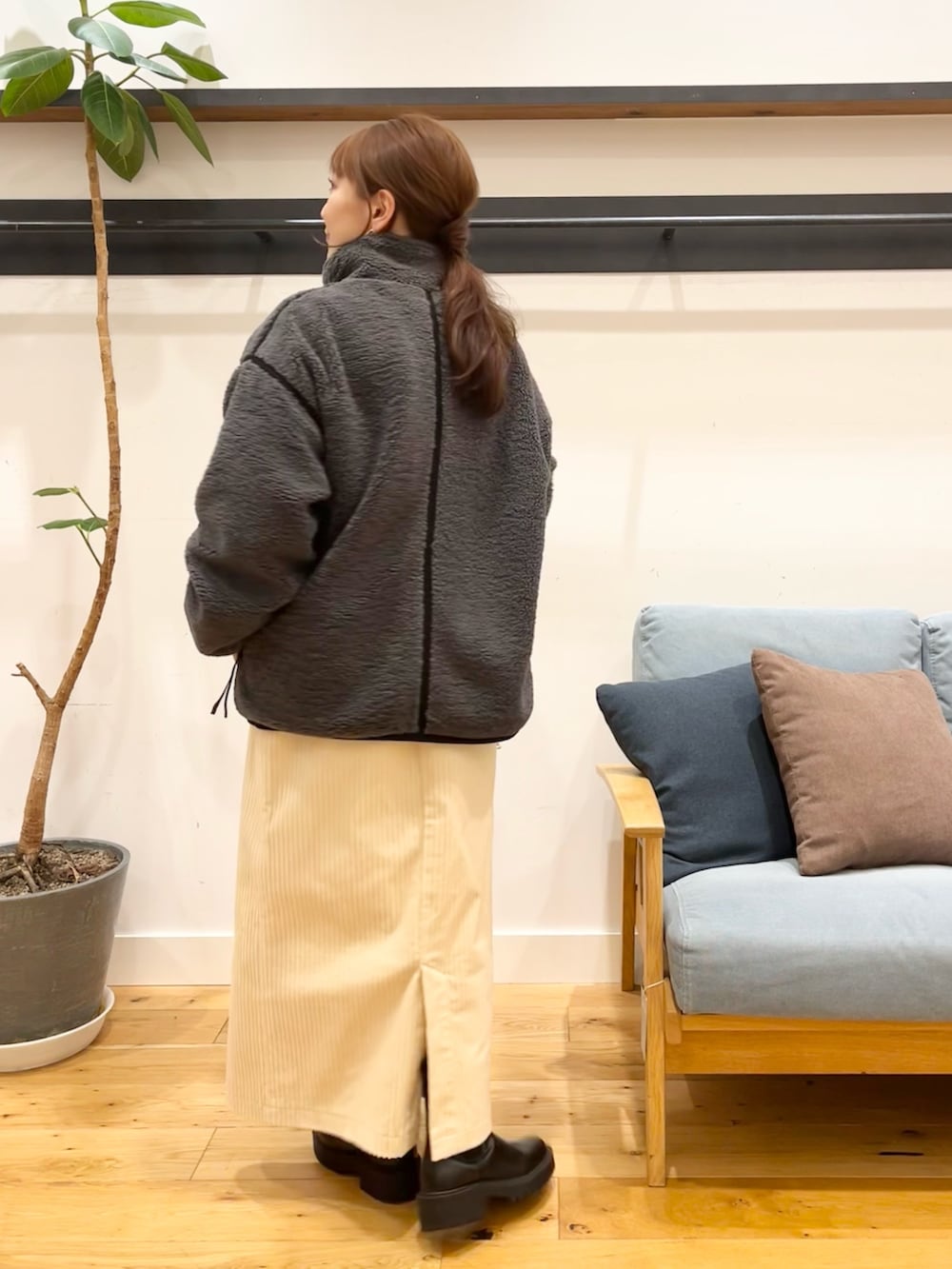 グレー系のブルゾン、ホワイト系のスカート、ブラック系のトートバッグを着用したレディースの冬コーディネートの2枚目の写真