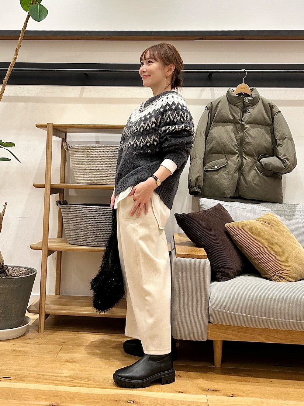 グレー系のニット/セーター、ブラウン系のトートバッグ、ホワイト系のスカートを着用したレディースの冬コーディネートの2枚目の写真