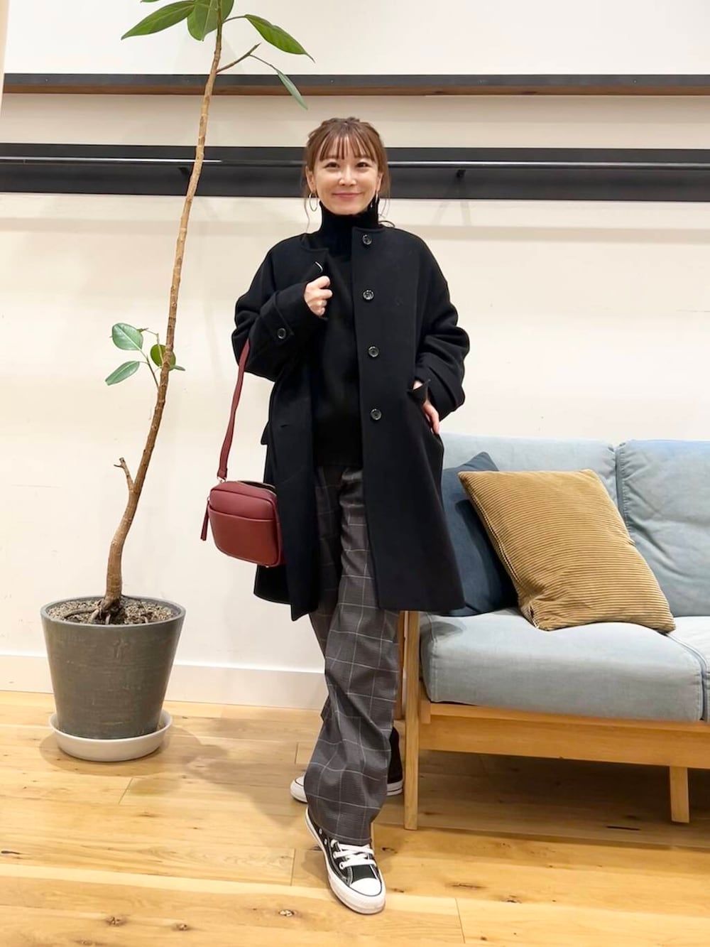 ブラック系のノーカラーコート、レッド系のショルダーバッグ、ブラック系のニット/セーターを着用したレディースの冬コーディネートの5枚目の写真