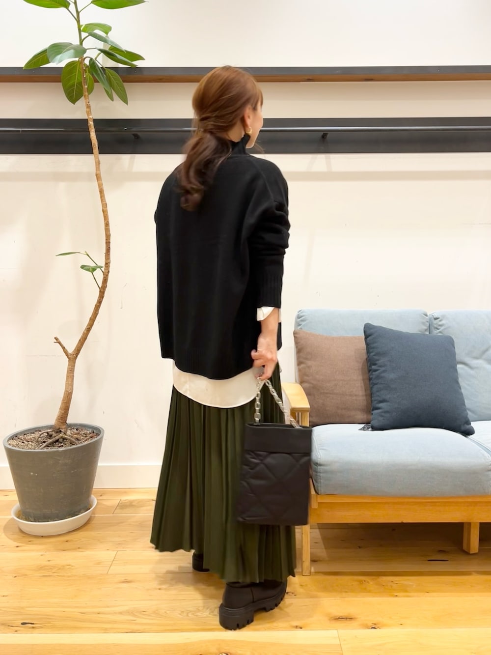 ブラック系のニット/セーター、グリーン系のスカート、ブラック系のショルダーバッグを着用したレディースの冬コーディネートの3枚目の写真