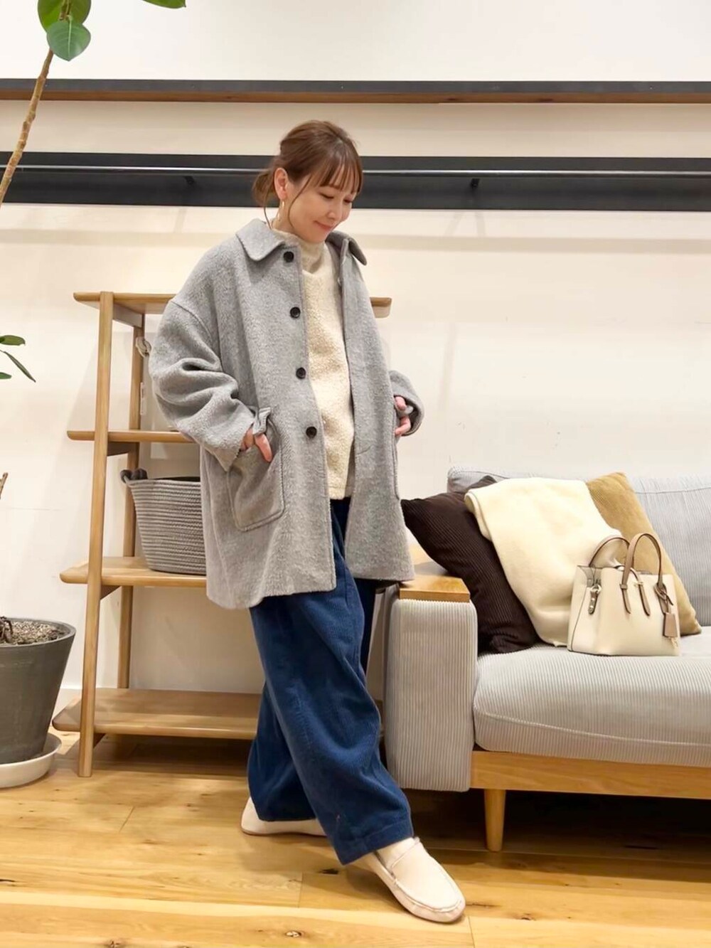 ホワイト系のハンドバッグ、グレー系のその他アウター、ホワイト系のスリッポンを着用したレディースの冬コーディネートの6枚目の写真