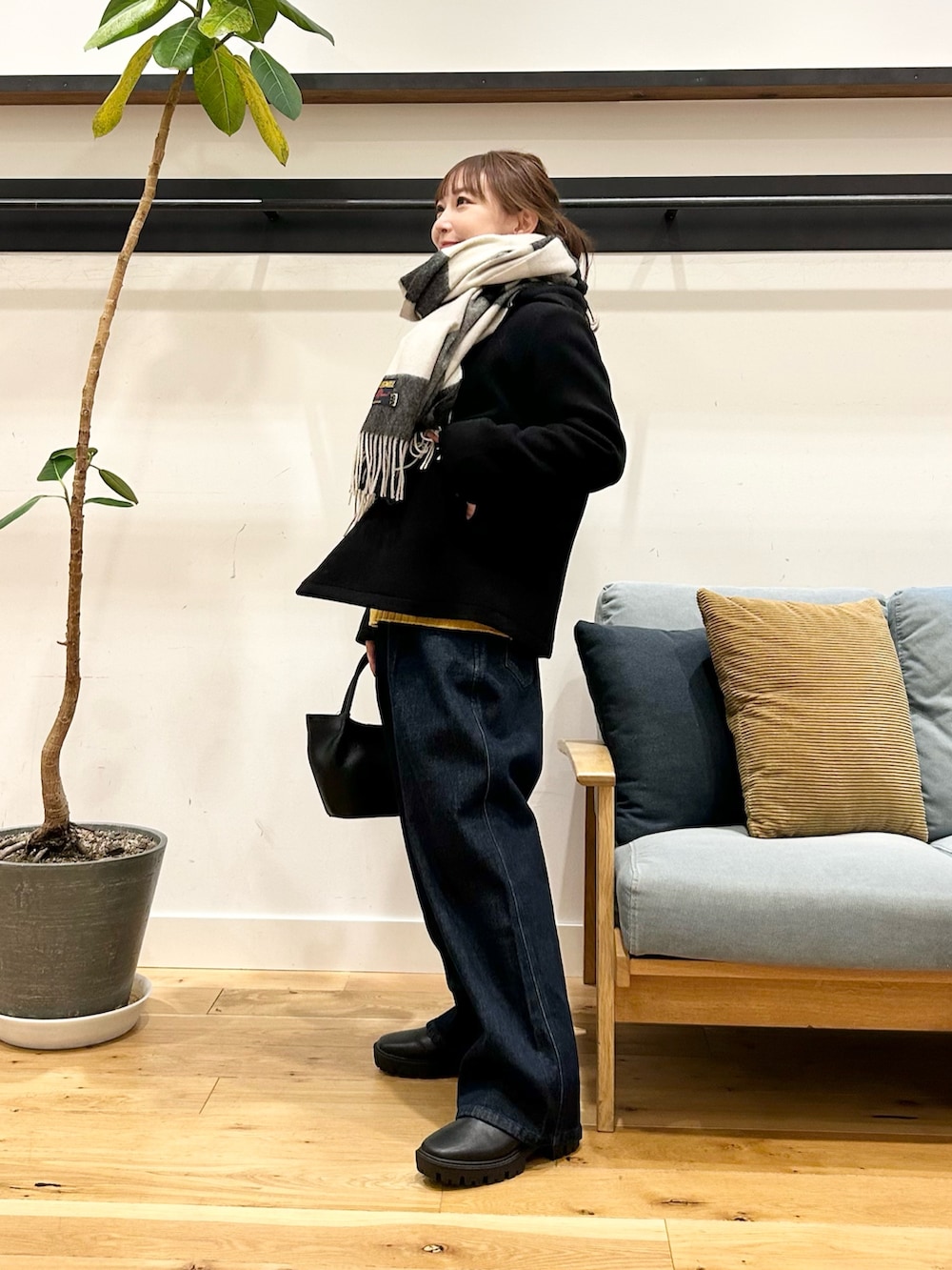 イエロー系のニット/セーター、ブルー系のデニムパンツ、ブラック系のショルダーバッグを着用したレディースの冬コーディネートの4枚目の写真