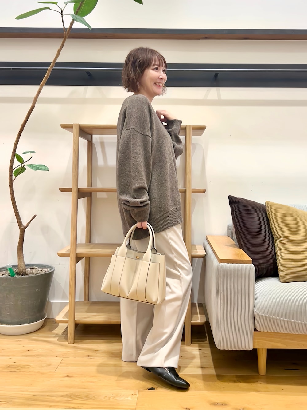 ブラウン系のニット/セーター、グレー系のその他パンツ、オレンジ系のトートバッグを着用したレディースの秋コーディネートの4枚目の写真