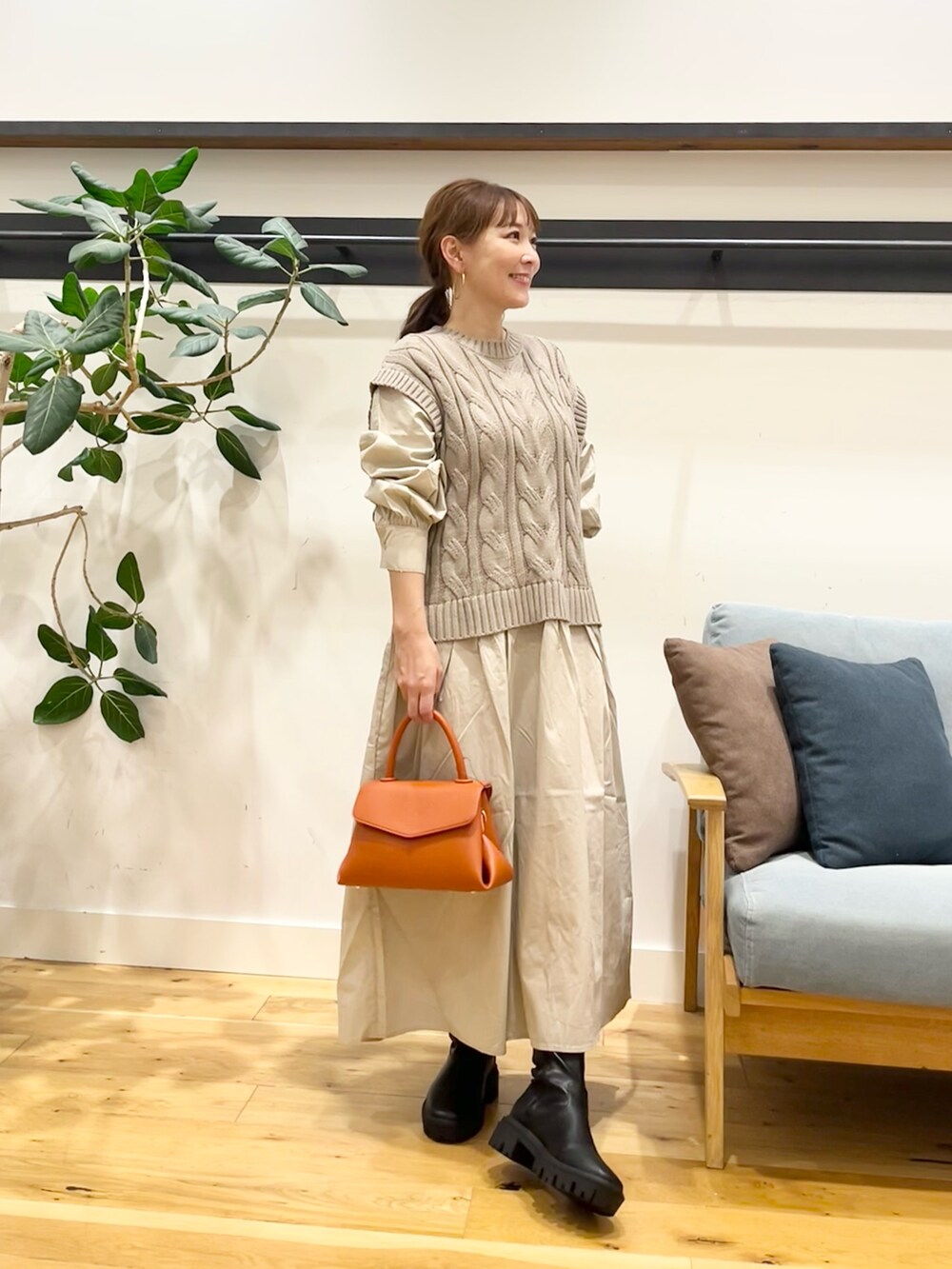 ベージュ系のワンピース、ブラック系のショルダーバッグ、ブラック系のブーツを着用したレディースの秋コーディネートの2枚目の写真