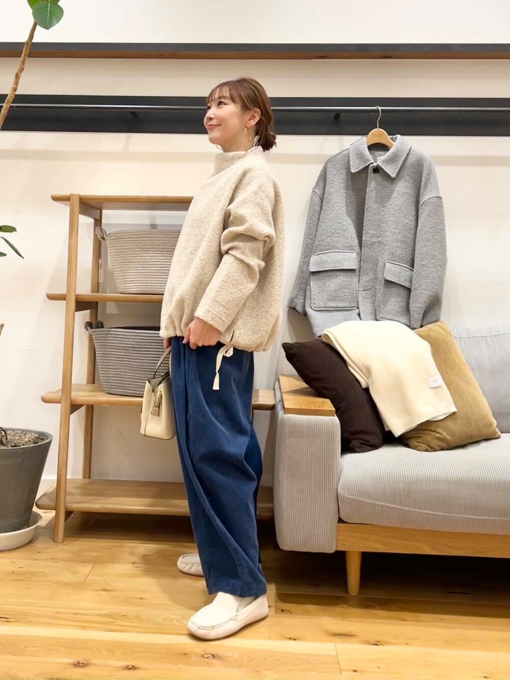 ホワイト系のハンドバッグ、グレー系のその他アウター、ホワイト系のスリッポンを着用したレディースの冬コーディネートの2枚目の写真