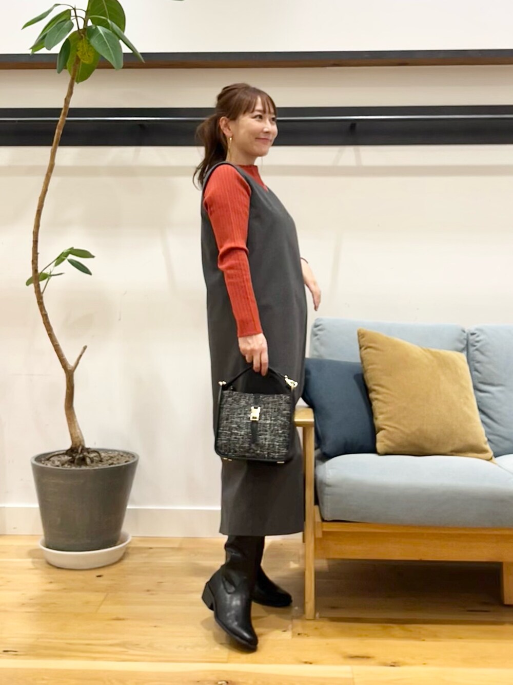 グレー系のワンピース、オレンジ系のニット/セーター、ブラック系のショルダーバッグを着用したレディースの秋コーディネートの3枚目の写真