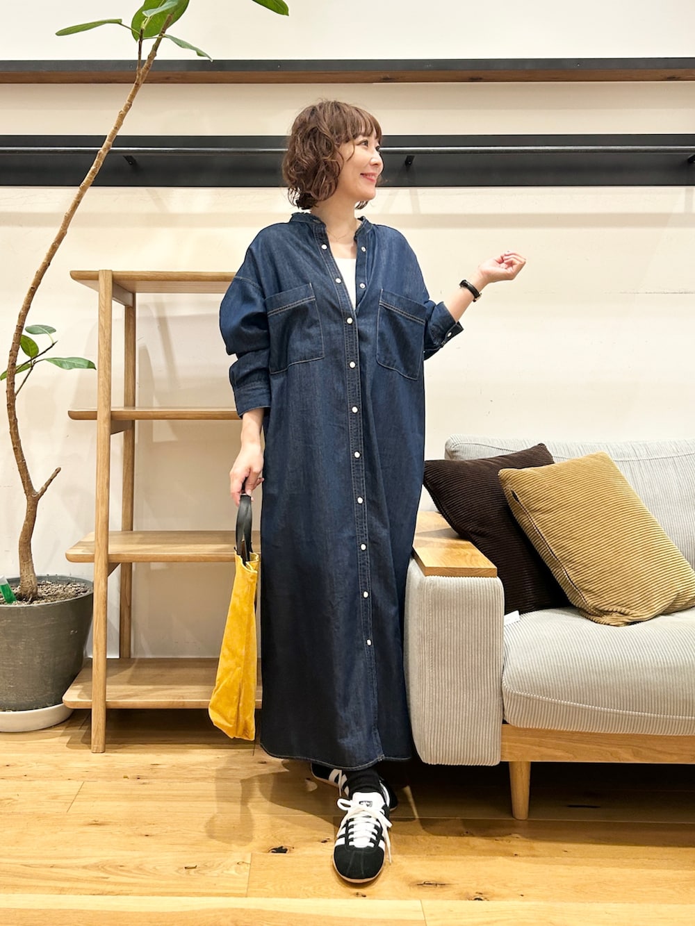 ブルー系のワンピース、オレンジ系のトートバッグ、ブラック系のスニーカーを着用したレディースの秋コーディネートの4枚目の写真