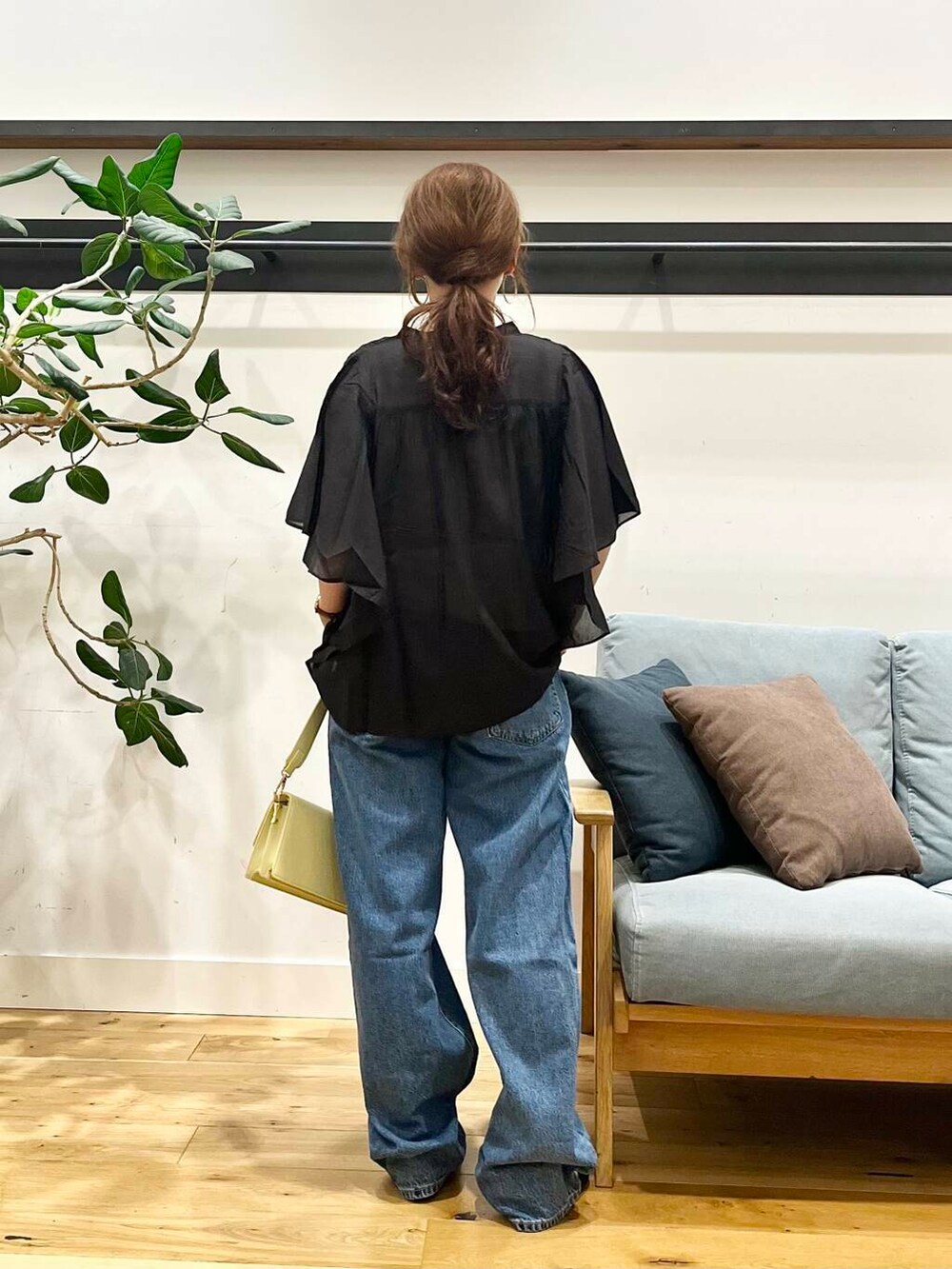 ブルー系のデニムパンツ、ブラック系のシャツ/ブラウス、イエロー系のショルダーバッグを着用したレディースの夏コーディネートの3枚目の写真