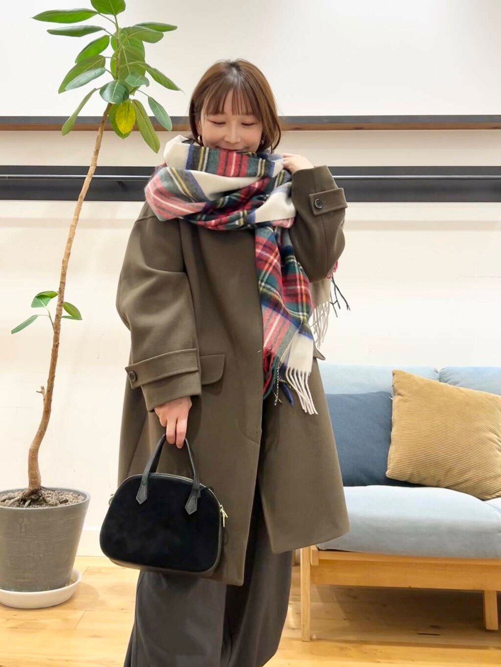 グリーン系のノーカラーコート、ホワイト系のニット/セーター、ブラック系のショルダーバッグを着用したレディースの冬コーディネートの2枚目の写真