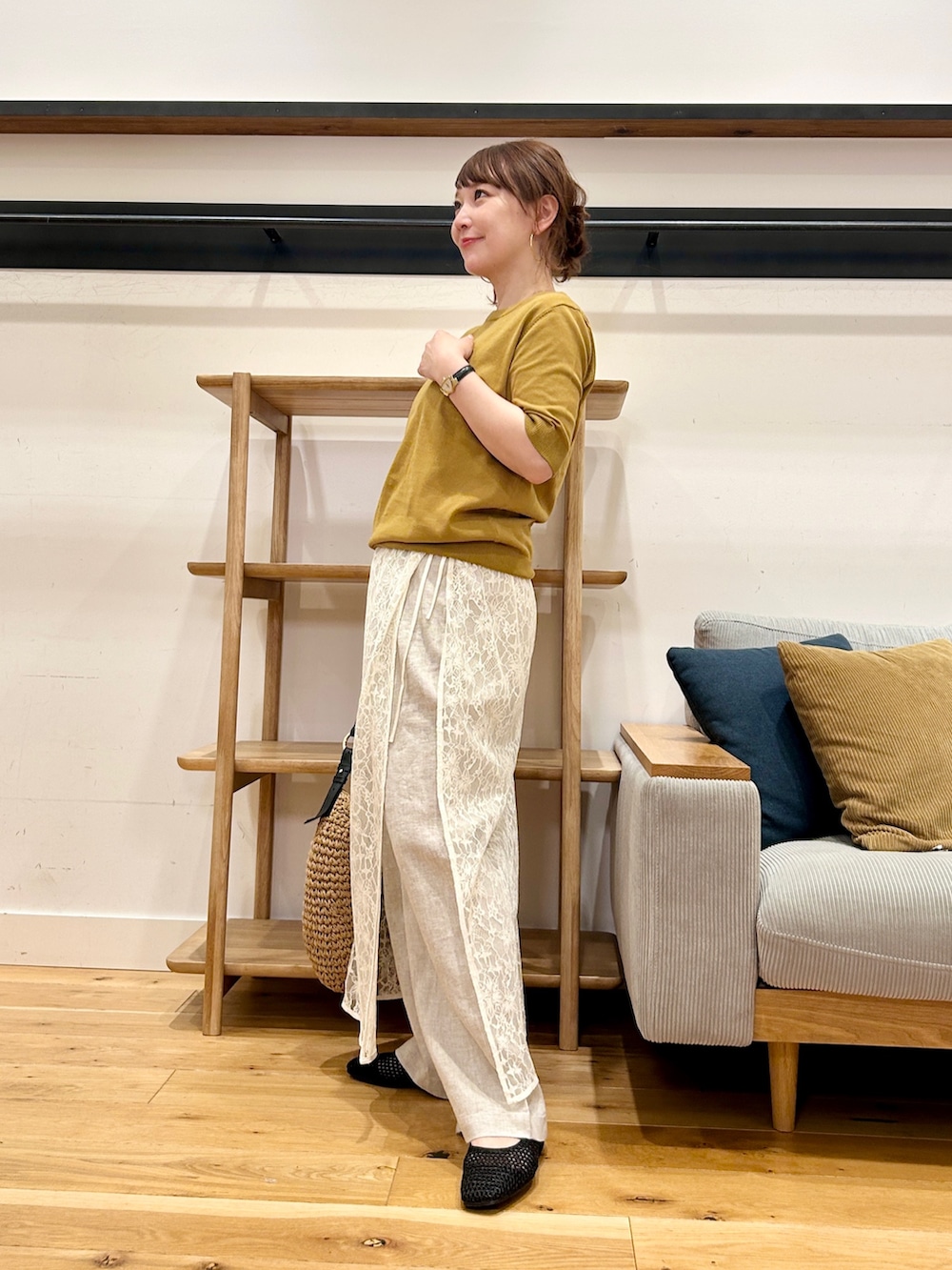 イエロー系のニット/セーター、ホワイト系のスカート、ベージュ系のトートバッグを着用したレディースの春コーディネートの3枚目の写真