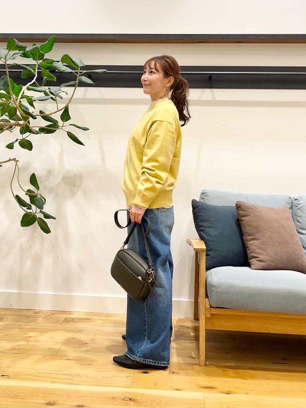 ブルー系のデニムパンツ、グリーン系のショルダーバッグ、ブラック系のその他シューズを着用したレディースの秋コーディネートの4枚目の写真