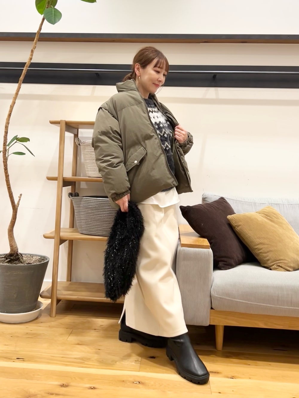 グレー系のニット/セーター、ブラウン系のトートバッグ、ホワイト系のスカートを着用したレディースの冬コーディネートの5枚目の写真