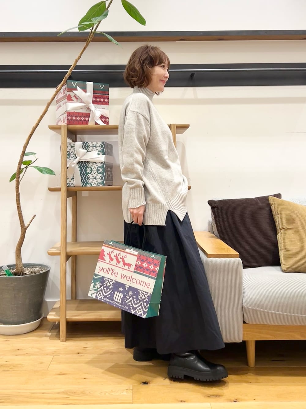 グレー系のニット/セーター、ブルー系のスカート、ブラック系のブーツを着用したレディースの冬コーディネートの3枚目の写真