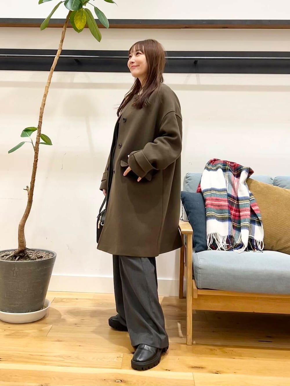 グリーン系のノーカラーコート、ホワイト系のニット/セーター、ブラック系のショルダーバッグを着用したレディースの冬コーディネートの4枚目の写真