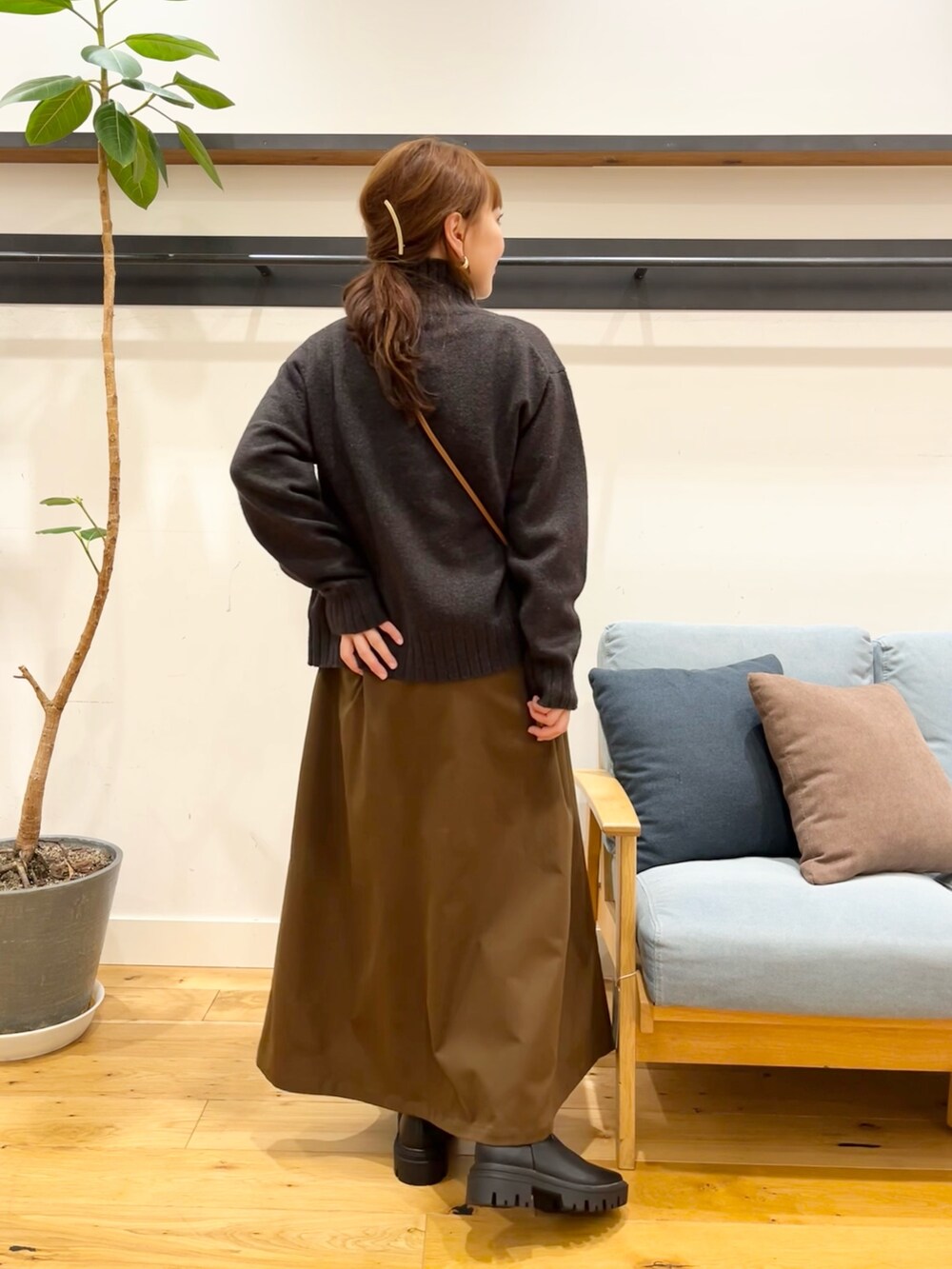 ブルー系のニット/セーター、ブラック系のショルダーバッグ、ブラウン系のスカートを着用したレディースの冬コーディネートの3枚目の写真