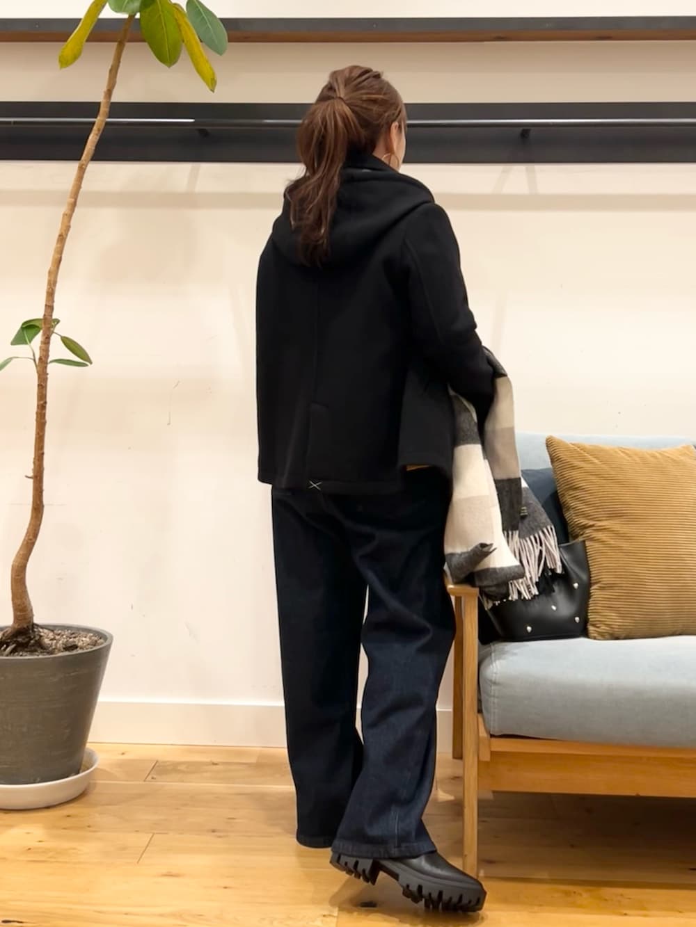 イエロー系のニット/セーター、ブルー系のデニムパンツ、ブラック系のショルダーバッグを着用したレディースの冬コーディネートの5枚目の写真