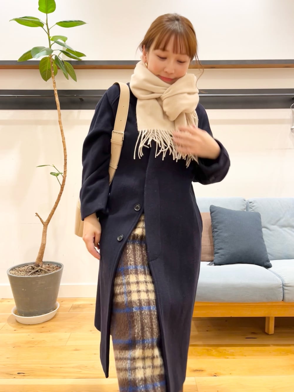 グレー系のステンカラーコート、ブラウン系のスカート、ブラック系のブーツを着用したレディースの冬コーディネートの4枚目の写真