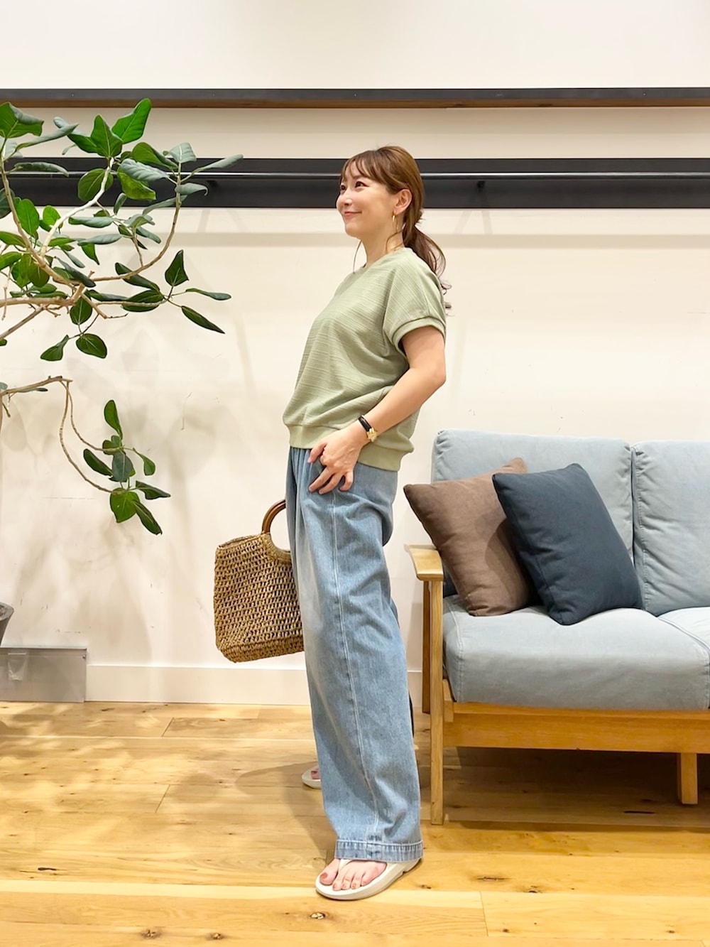 グリーン系のTシャツ/カットソー、ブルー系のデニムパンツ、ブラック系のかごバッグを着用したレディースの秋コーディネートの2枚目の写真